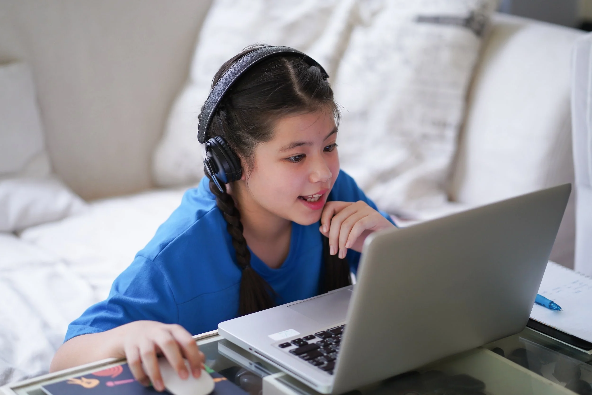 A young girl wearing headphones logs on to a game on her laptop computer.