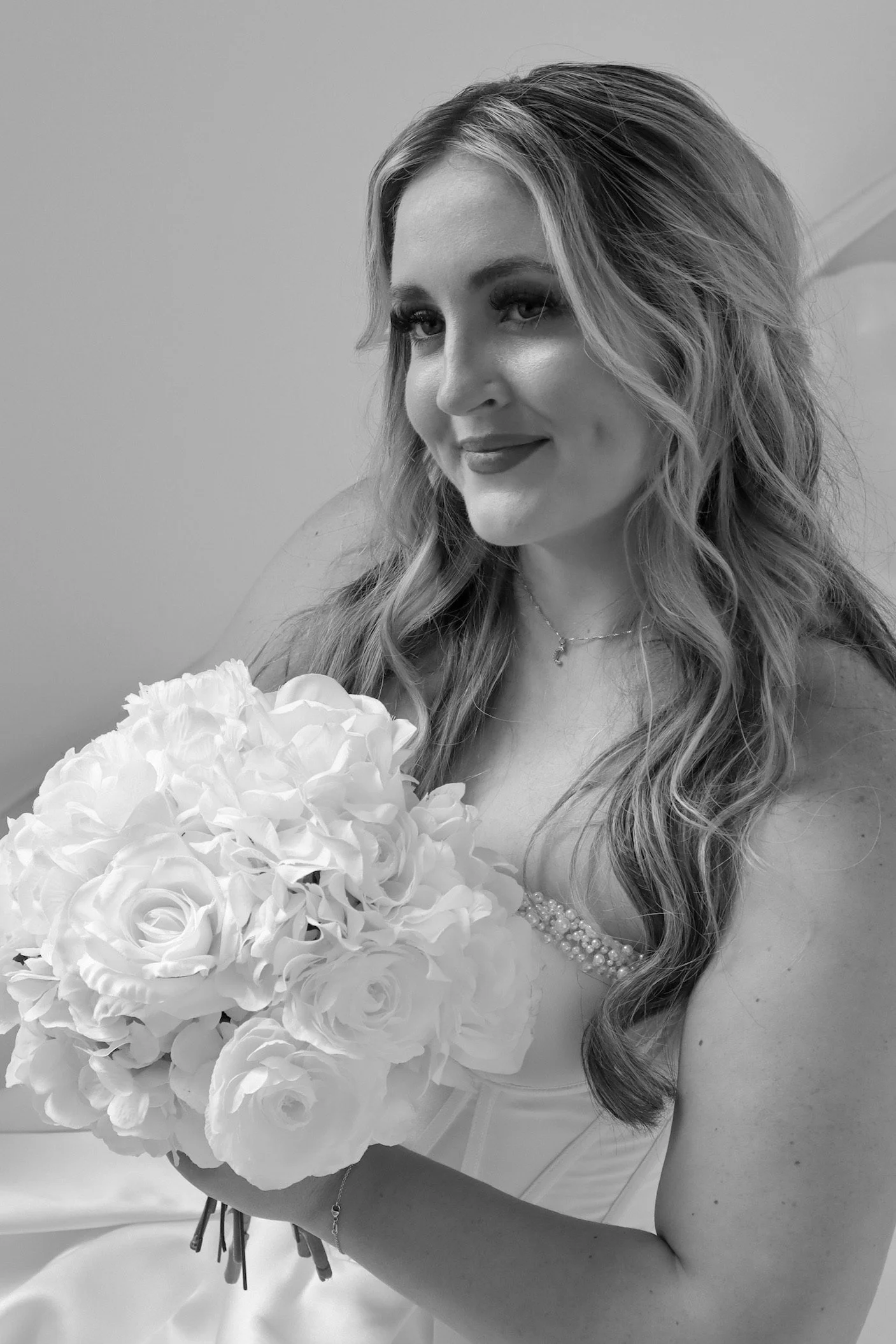 Black and white photo of a smiling woman holding a bouquet of flowers.