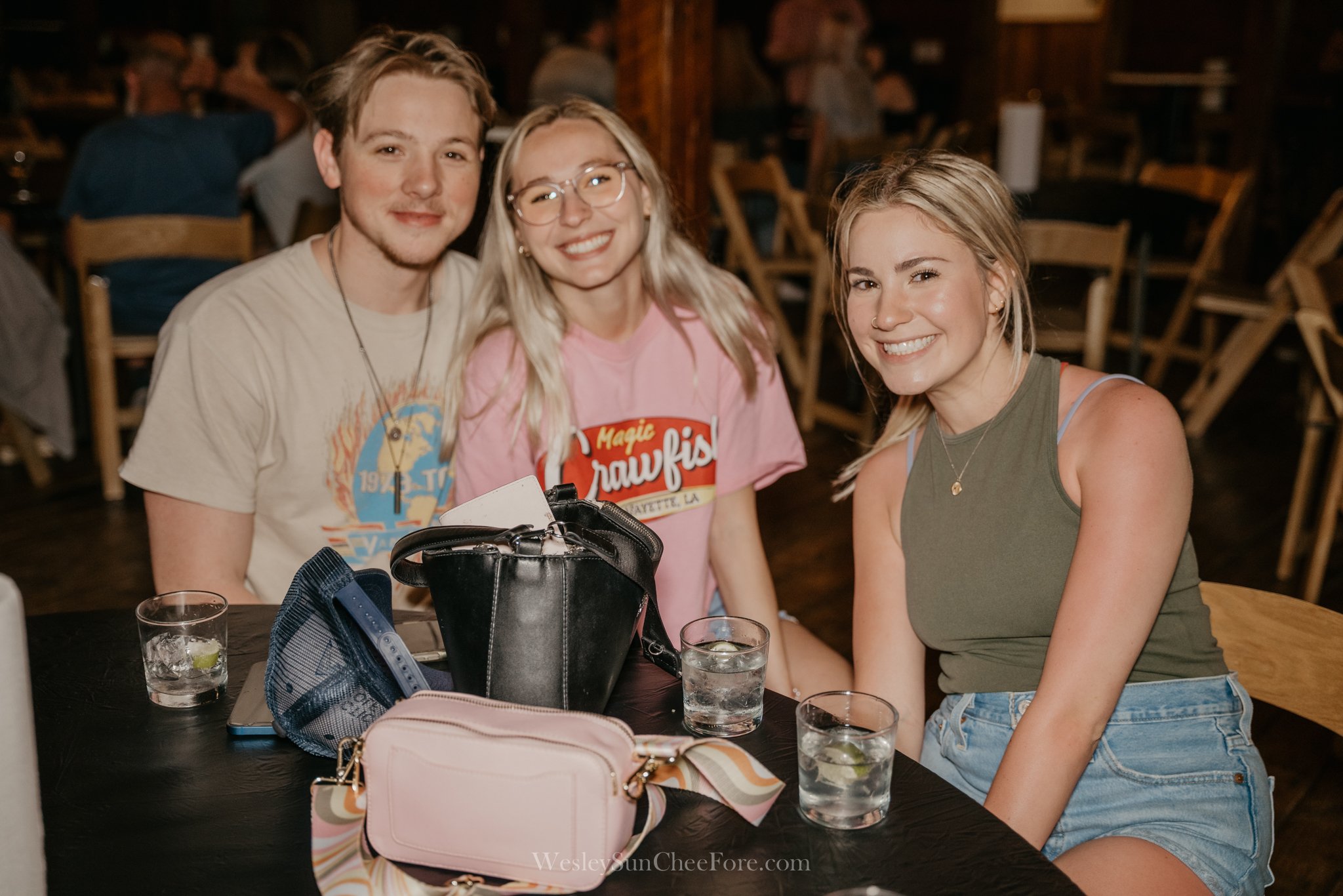 Three young women sitting at a table in a restaurant, smiling at the camera.