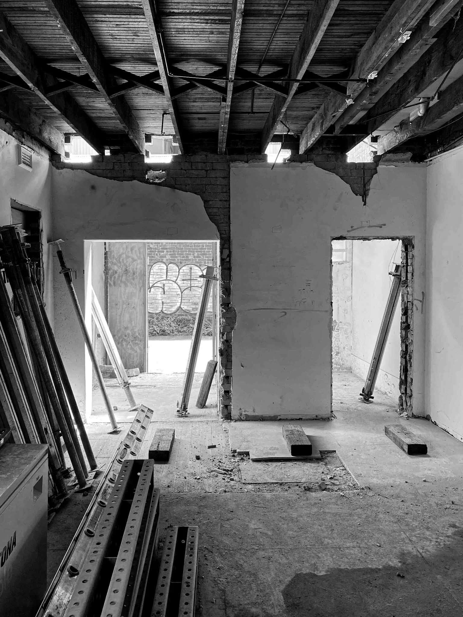 Interior of a building under construction with exposed beams, partially demolished walls, and construction supports.