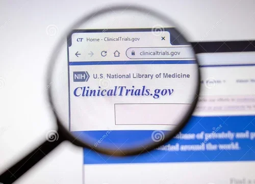 A computer screen showing the website clinicaltrials.gov through a magnifying glass.