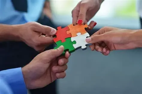 Multiple hands connecting a multicolored jigsaw puzzle piece.