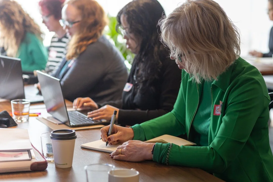women in workshop sitting an looking to laptop with back light