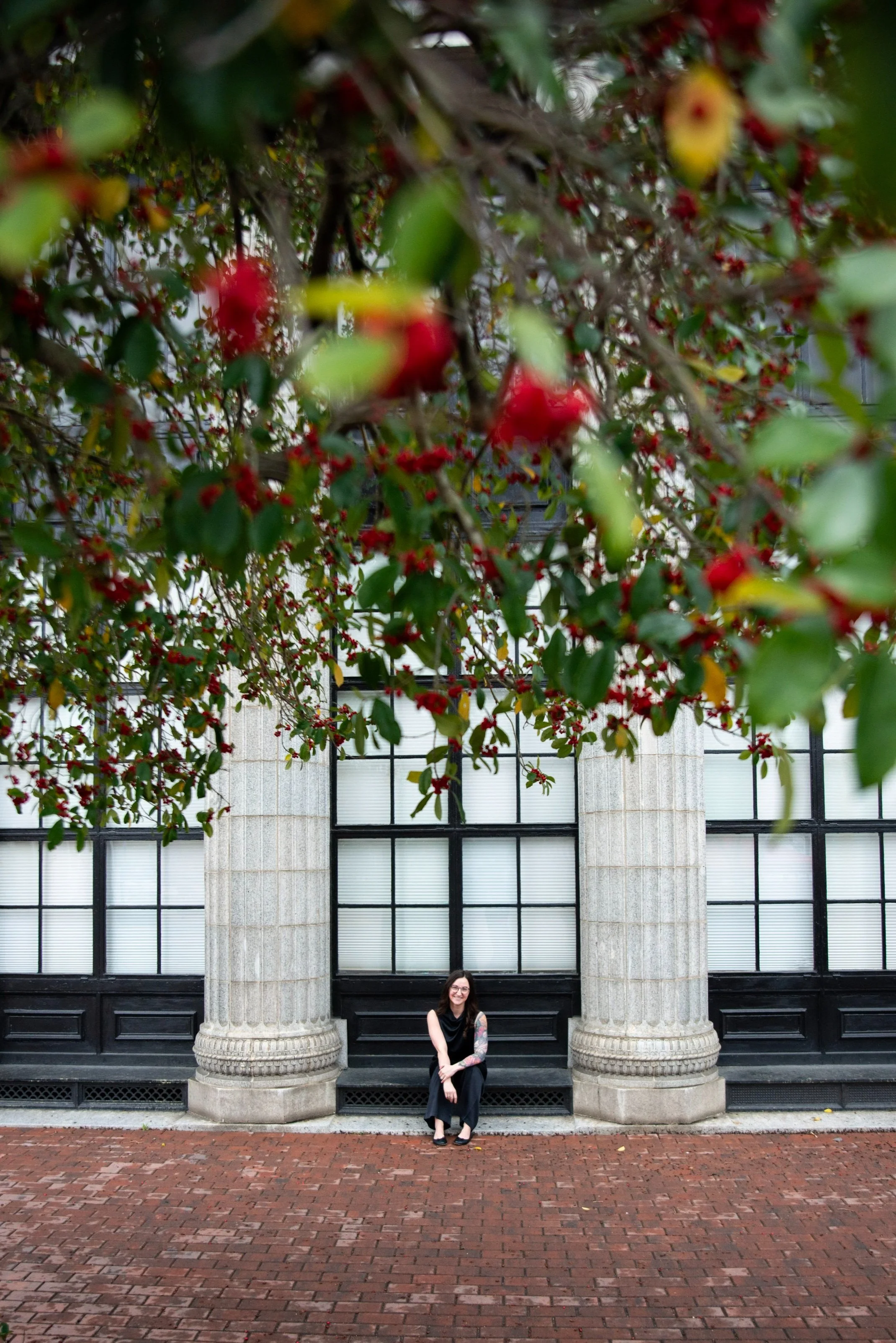 Kristin Dain, a marketing analyst trained in Power BI, DAX, SQL, Python, and Technical Program Management through Microsoft’s Software & Systems Academy (MSSA), seated beneath a fruit tree outside a corporate building.