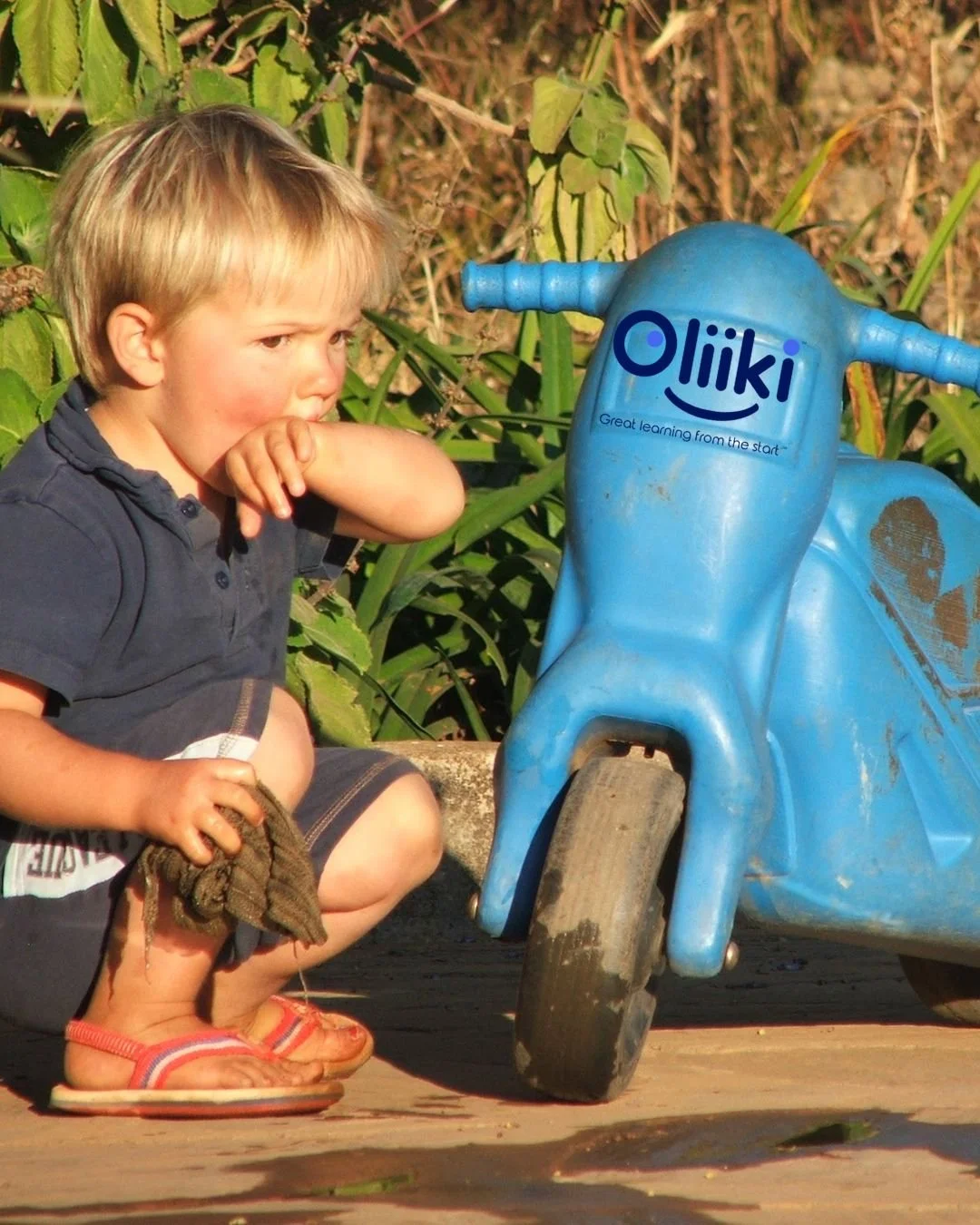 Small child washing a plastic motorbike