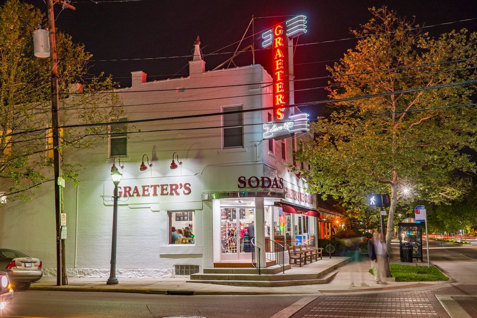 Exterior of Graeter's ice cream parlor at night with neon sign and people outside.