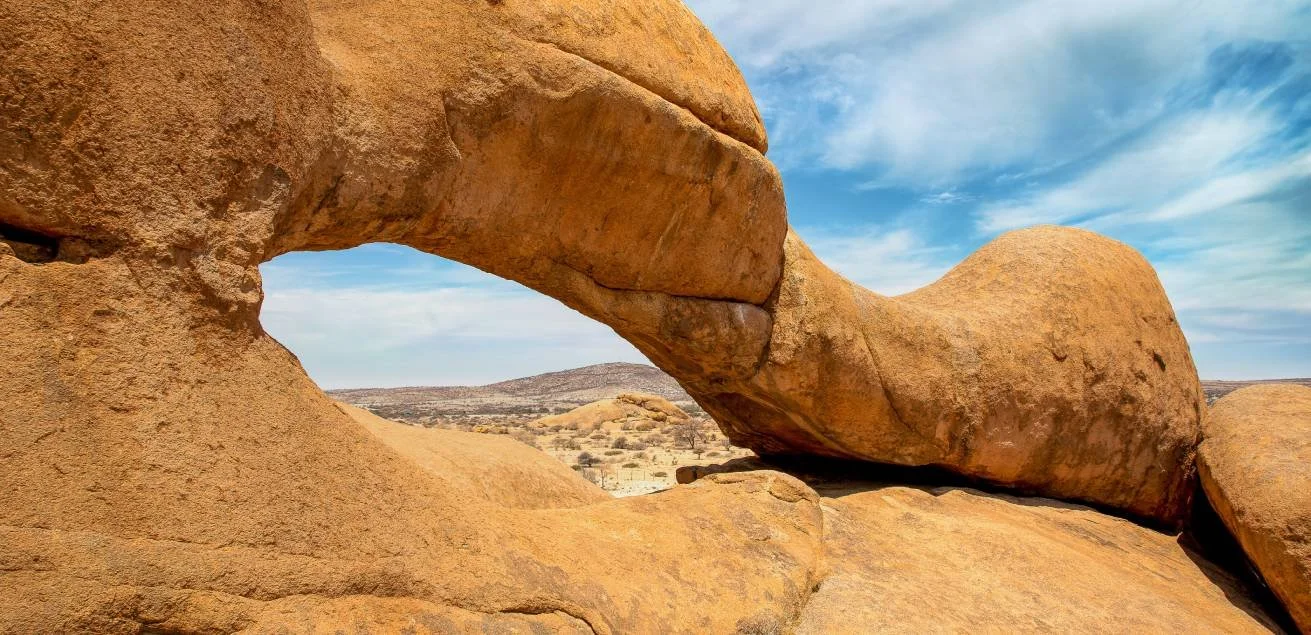 The iconic natural rock arch at Spitzkoppe in Namibia, with warm granite formations set against a clear blue sky, one of the country’s most striking geological attractions.