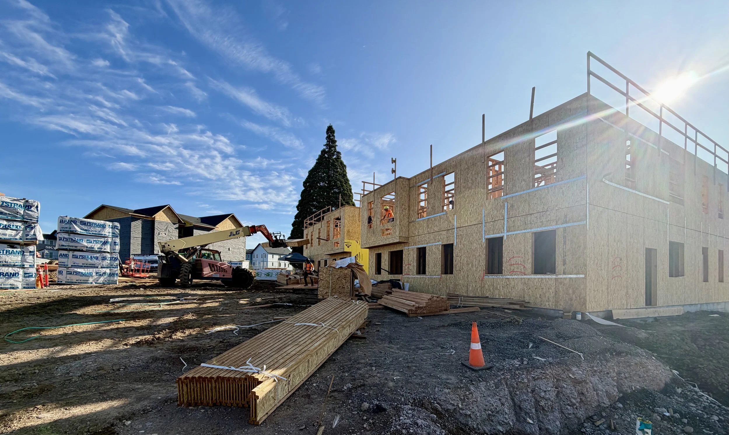 Wood-framed multifamily building under construction in Salem, Oregon, with telehandler on site