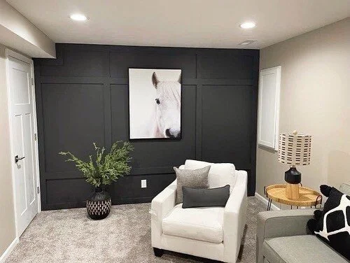 Living room with black accent wall, white armchair with pillows, a potted plant, and a framed horse painting.