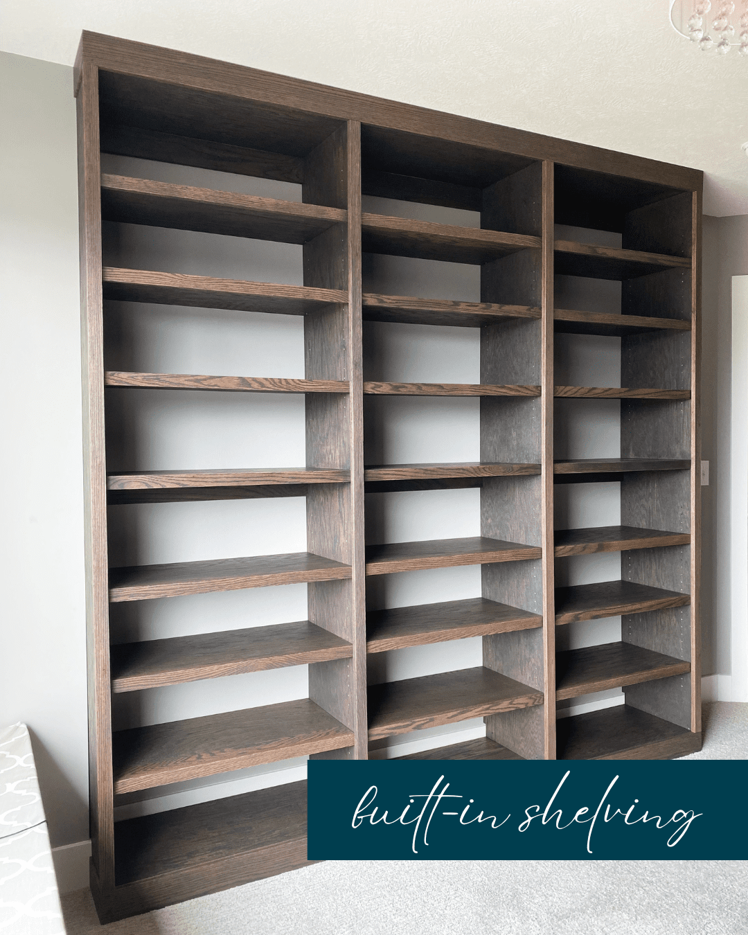Empty built-in wooden shelving unit in a room with a light-colored wall and carpeted floor.