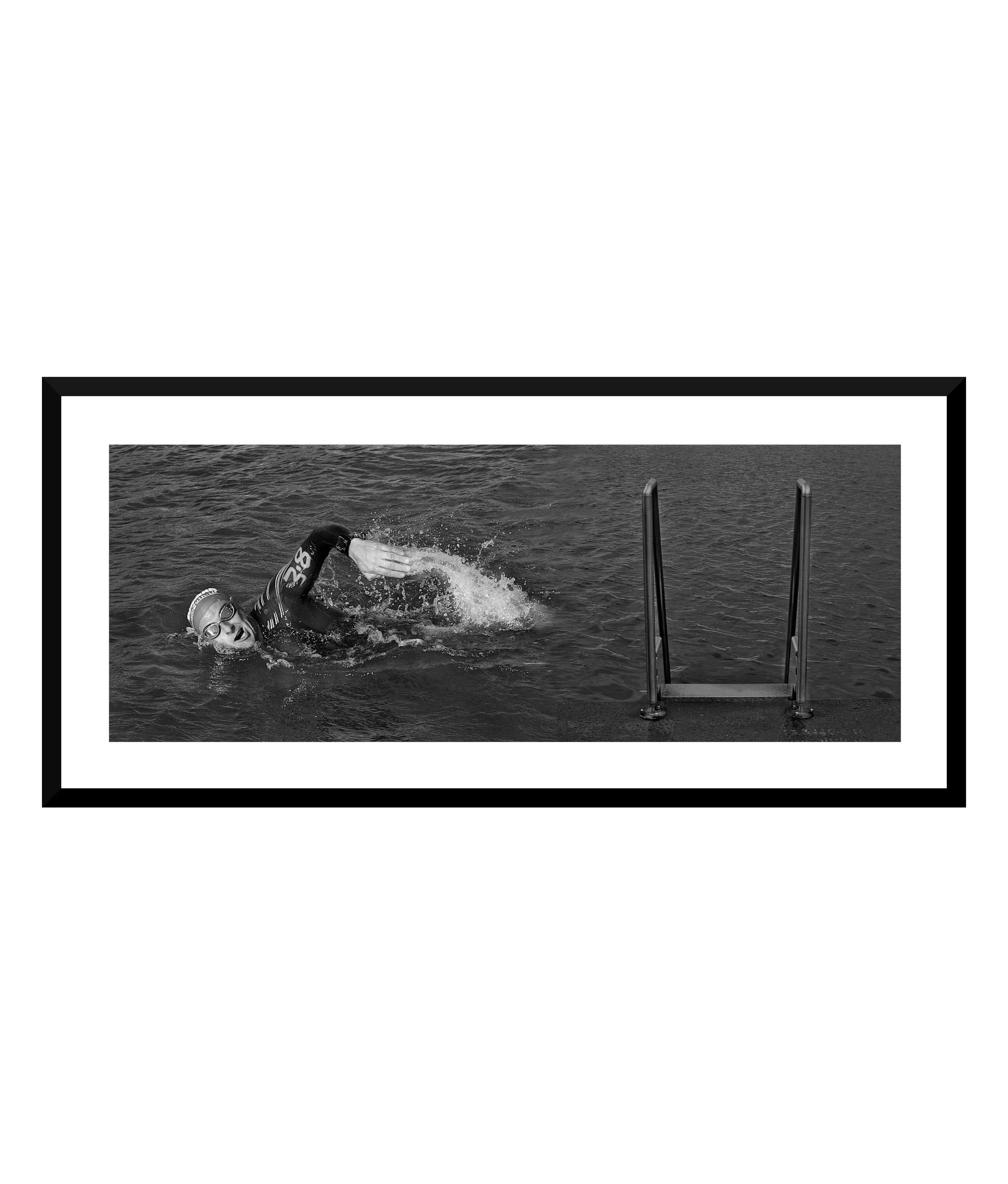 Swimmer in a black wetsuit swimming in open water near a ladder