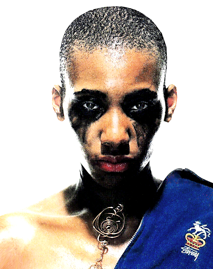 A person with short hair and black makeup around their eyes, wearing a blue garment with a crest and a spiral necklace, staring intensely at the camera against a white background.