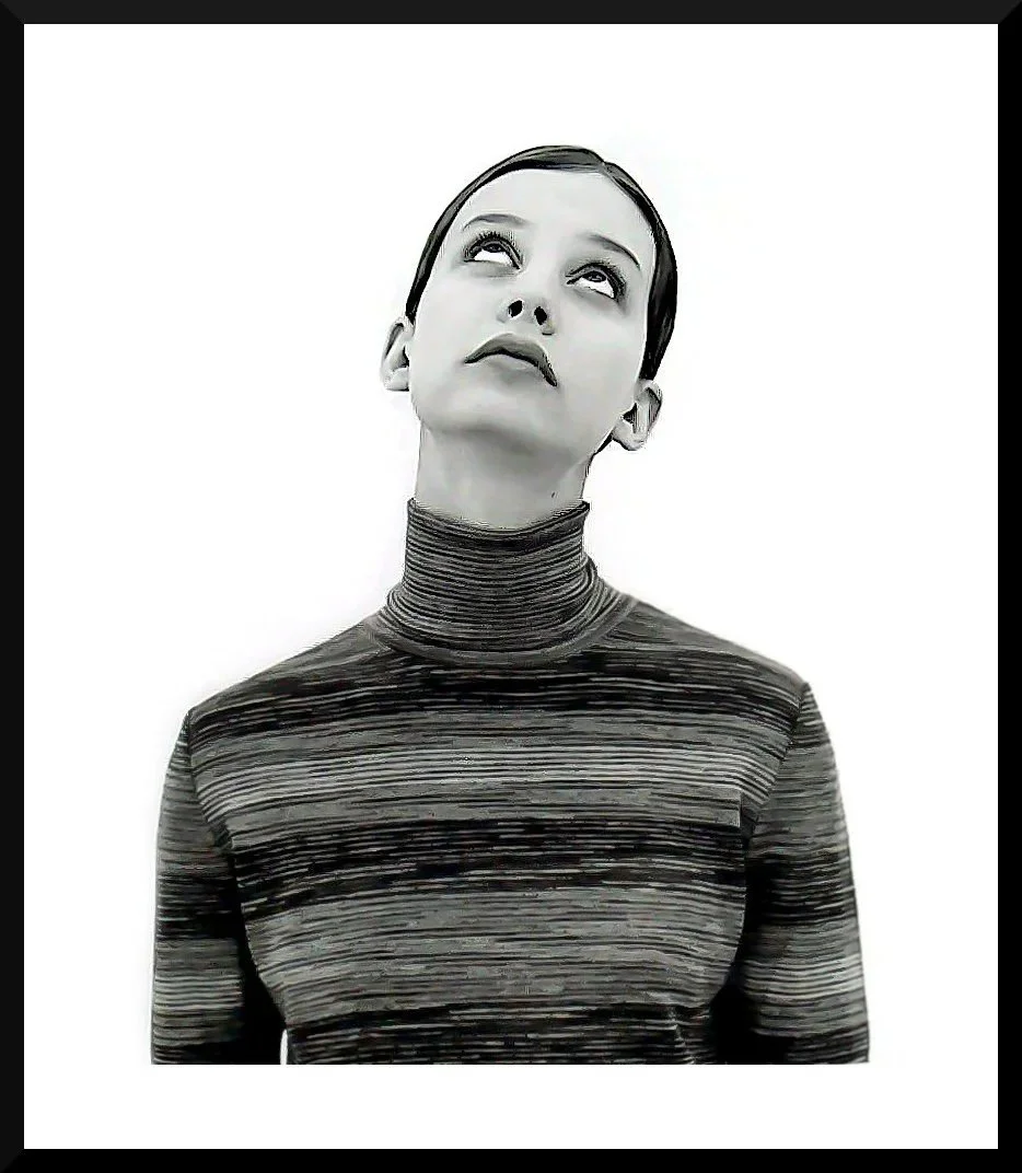 Black and white portrait of a woman with short hair, looking upward with a thoughtful expression, wearing a high-neck, striped top.