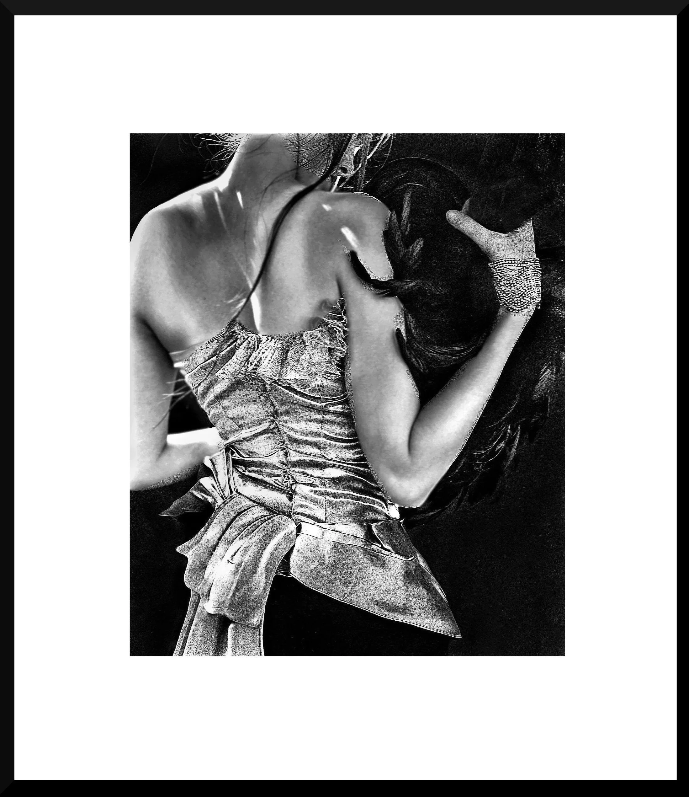 Black and white photograph of a woman with long, dark hair lying on her side with her eyes closed, wearing a satin evening gown with ruffled details and a rhinestone bracelet, on a dark background.