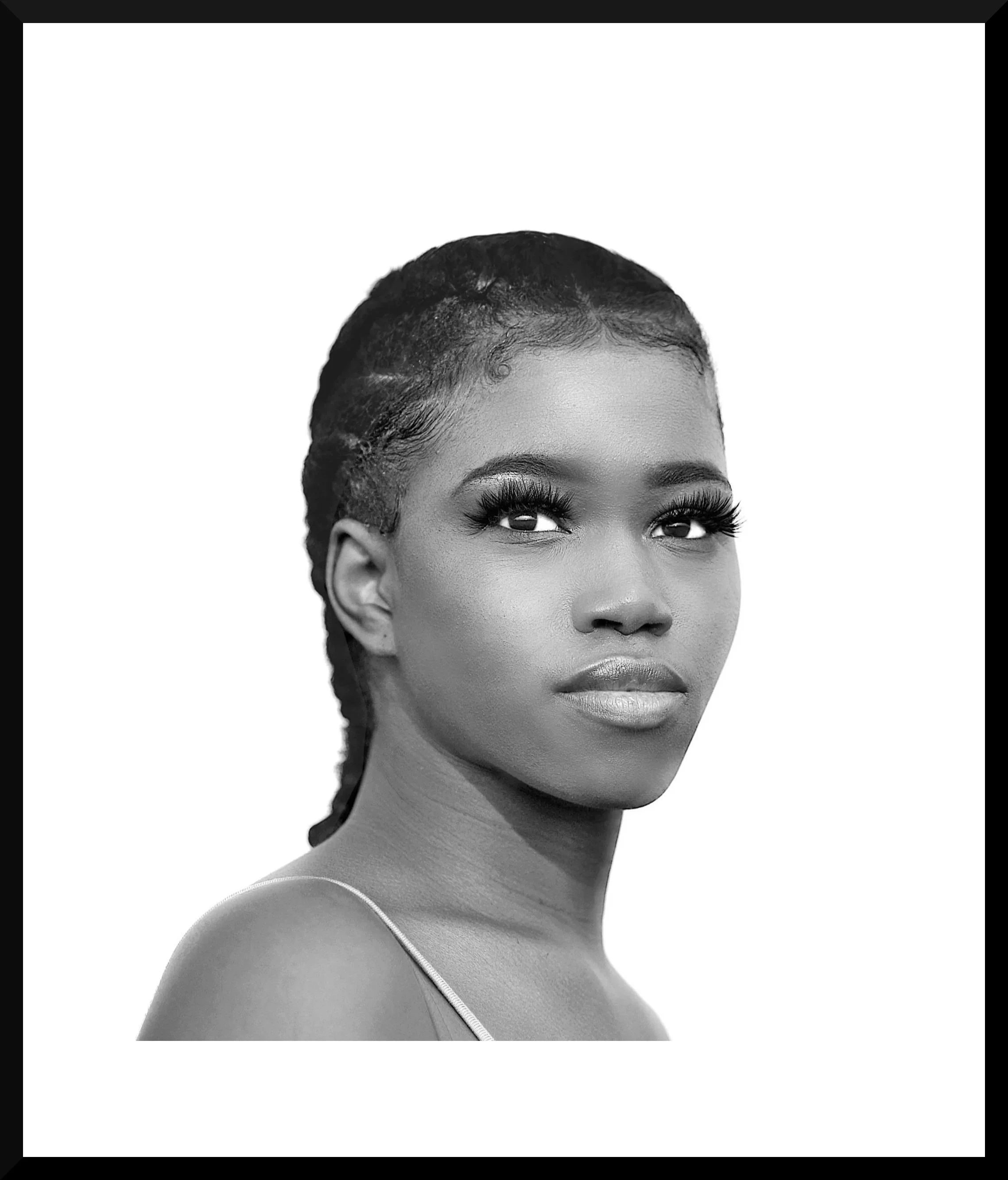 A black and white portrait of a woman with braided hair and dramatic eye makeup, looking slightly upward.