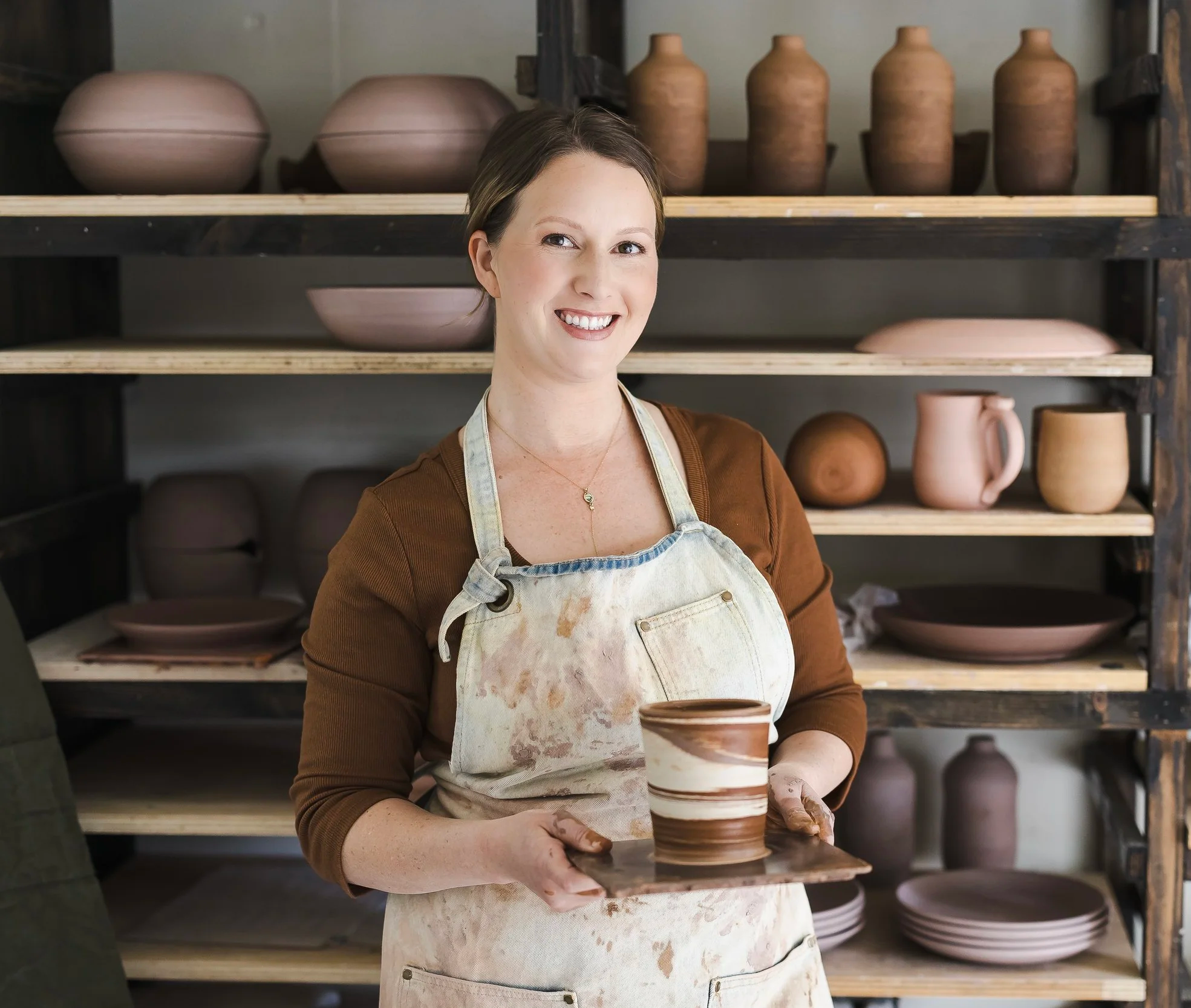 Ceramic artist Stephanie Hayes in her California Pottery Studio holding a handmade stoneware mug.