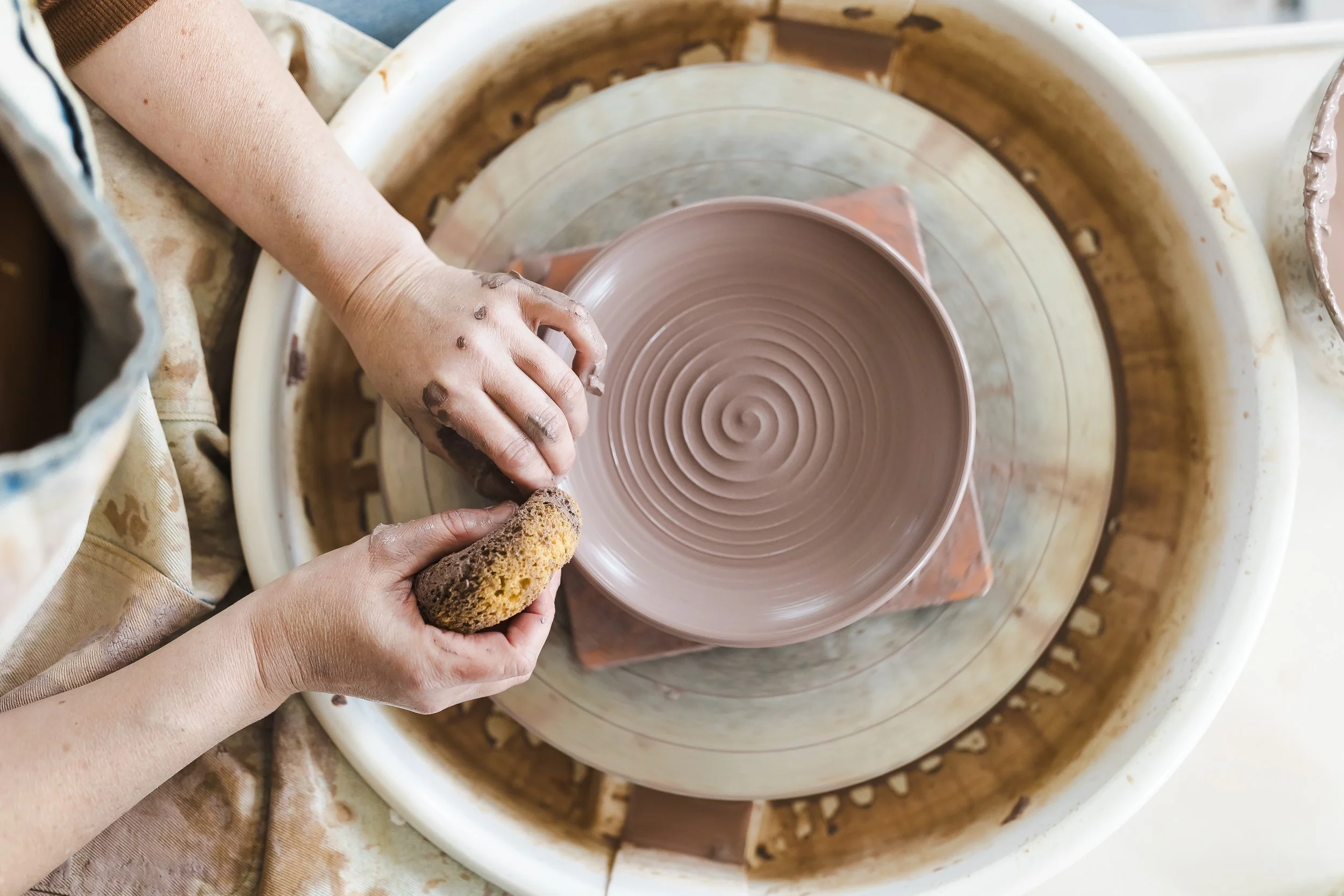 ceramic artist stephanie hayes shaping a handmade stoneware bowl on the pottery wheel in her california studio