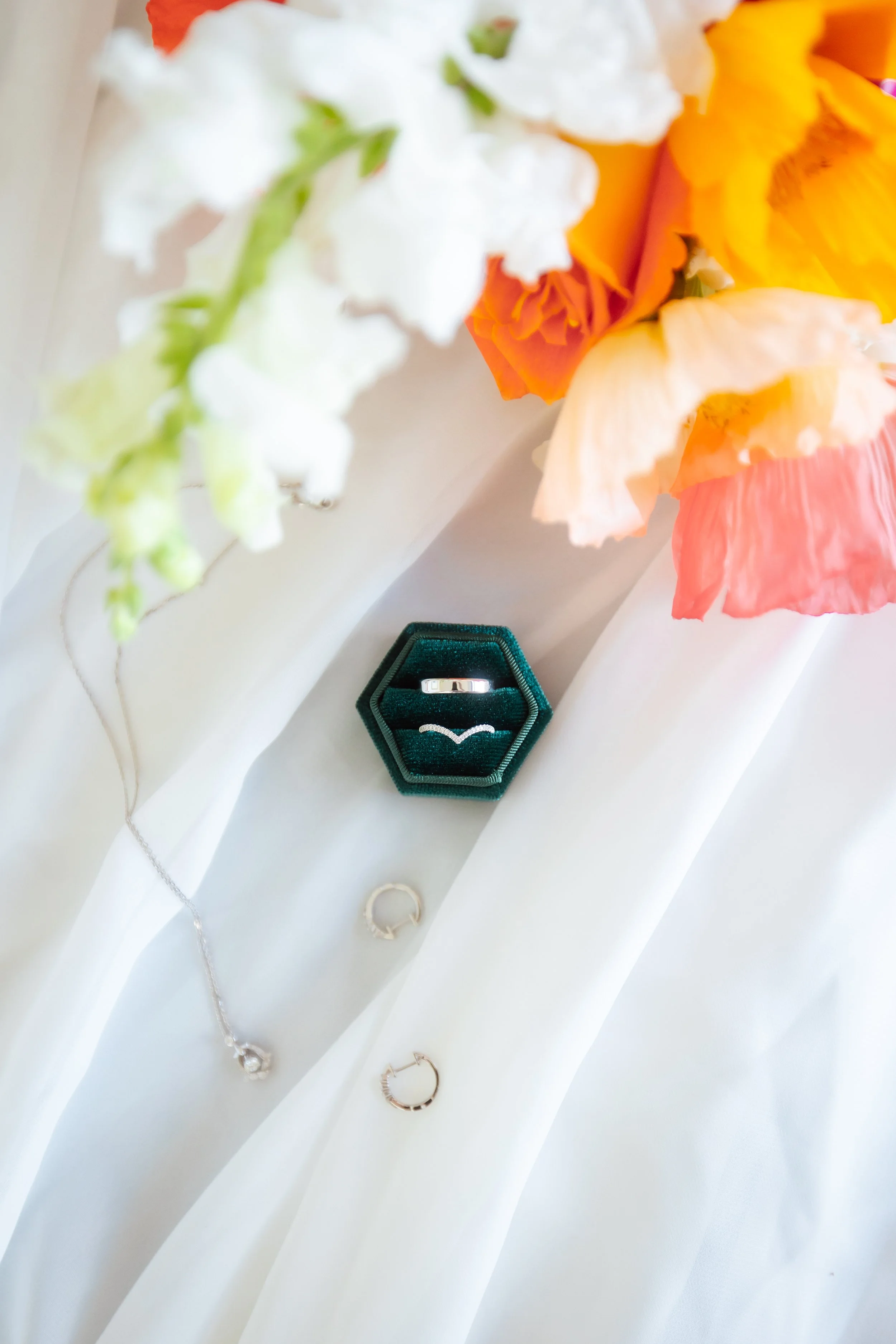 flat lay of rings bouquet and veil for wedding
