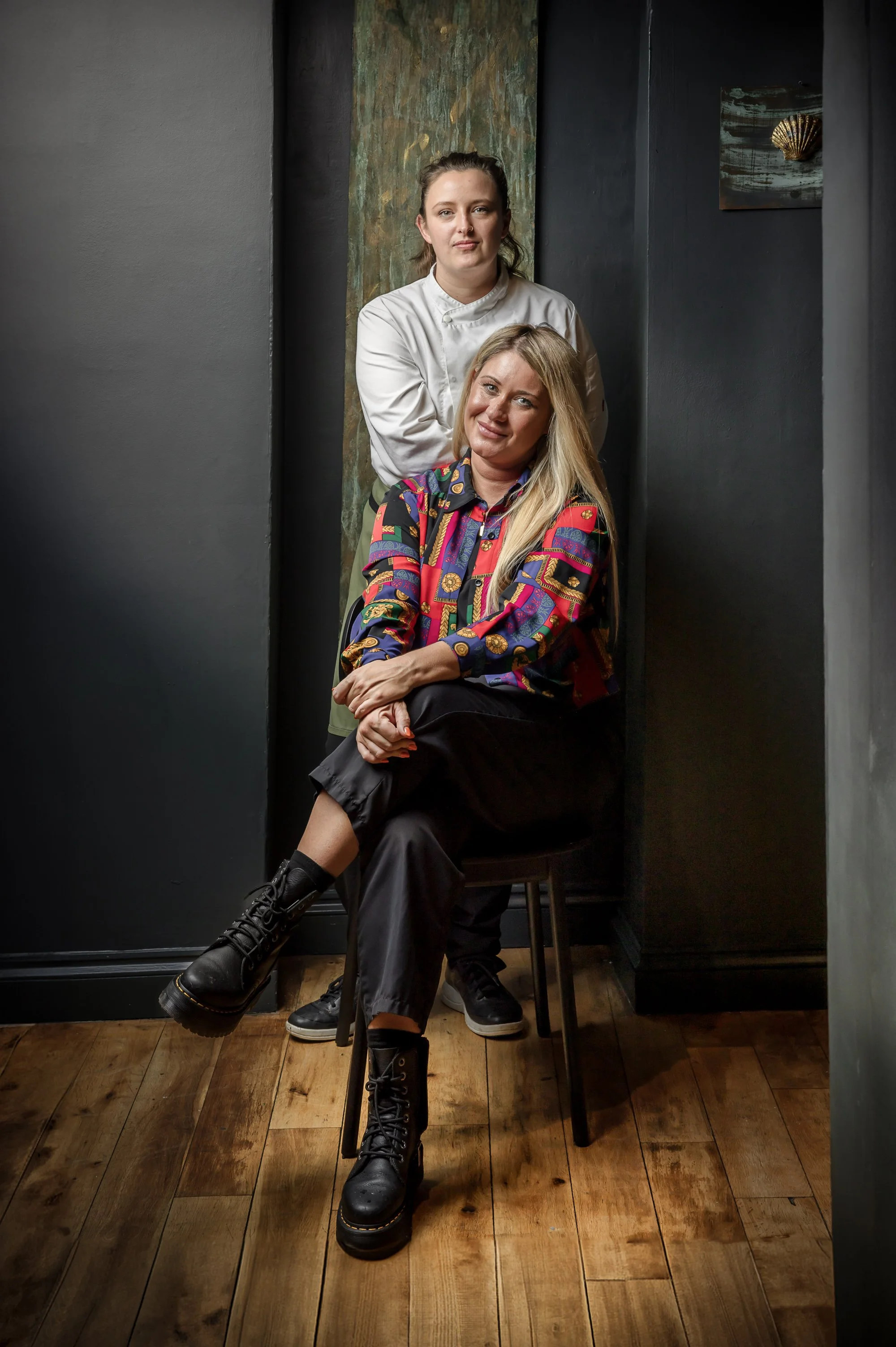 Environmental business portrait of two women posed together inside their workplace, using the surrounding interior and relaxed arrangement to present the people behind Idle Rock Hotel in Cornwall.