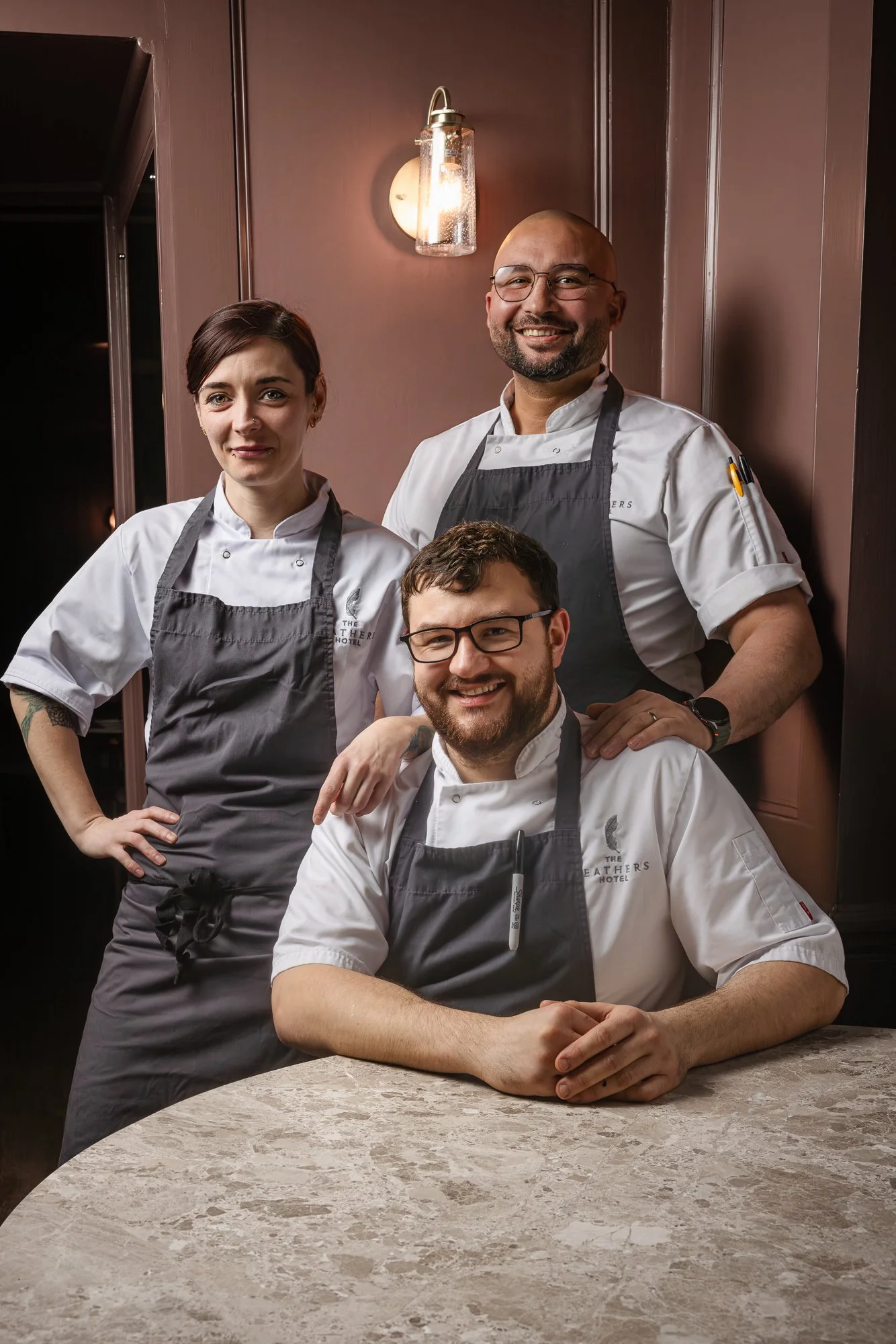 Commercial hospitality portrait of three chefs posed together in their restaurant, combining professional kitchen clothing with a relaxed team composition for The feathers Hotel  in Oxfordshire.