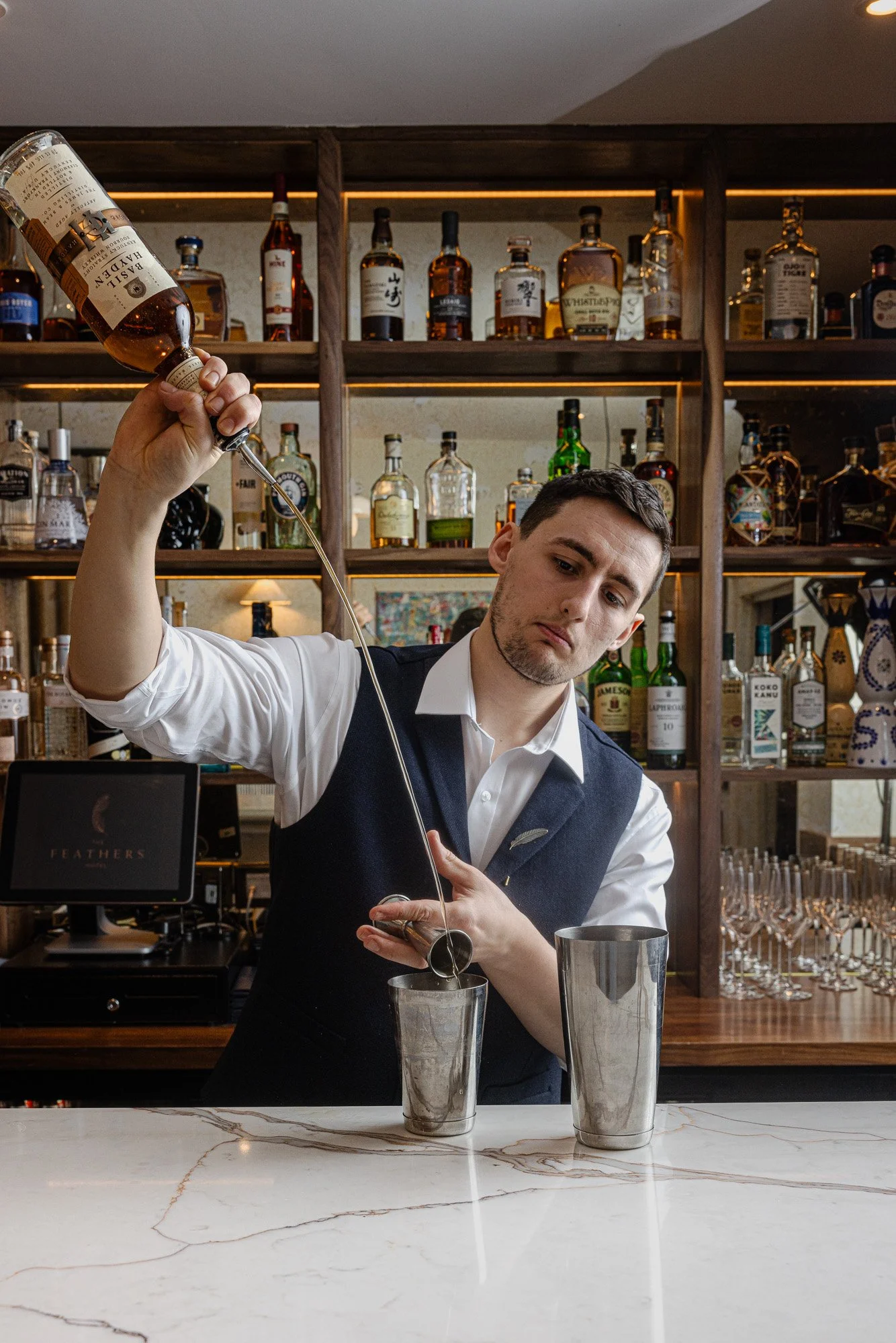 Hospitality photography, bartender free-pouring spirit into a jigger at the bar for website and PR, shot in Cheltenham, Gloucestershire, venue marketing in Reading, Berkshire, for use in London and Bath, Somerset.