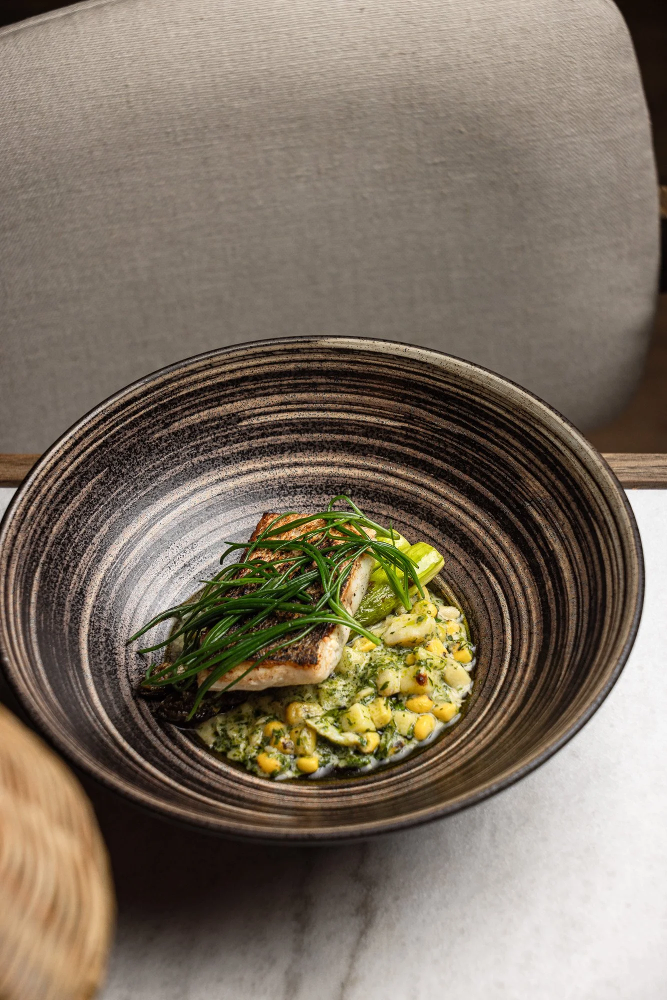 Commercial food photography, fish fillet with greens over sweetcorn ragout in a striped bowl for menus and web, shot in Poole, Dorset, venue marketing in Bath, Somerset, for use in London and Exeter, Devon.