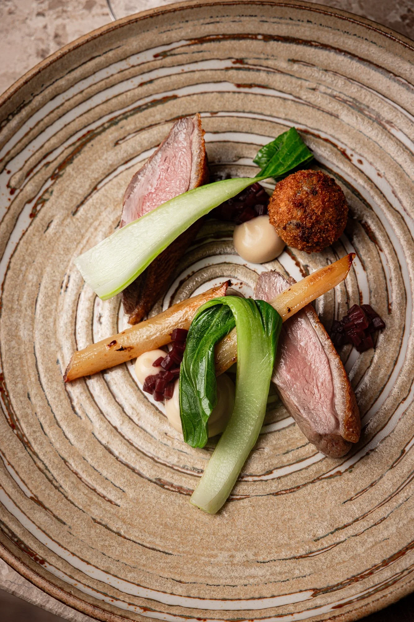 Professional restaurant plate, duck with greens and croquette in a textured bowl for menus and trade press, shot in Oxford, Oxfordshire, venue marketing in Reading, Berkshire, for use in London and Exeter, Devon.