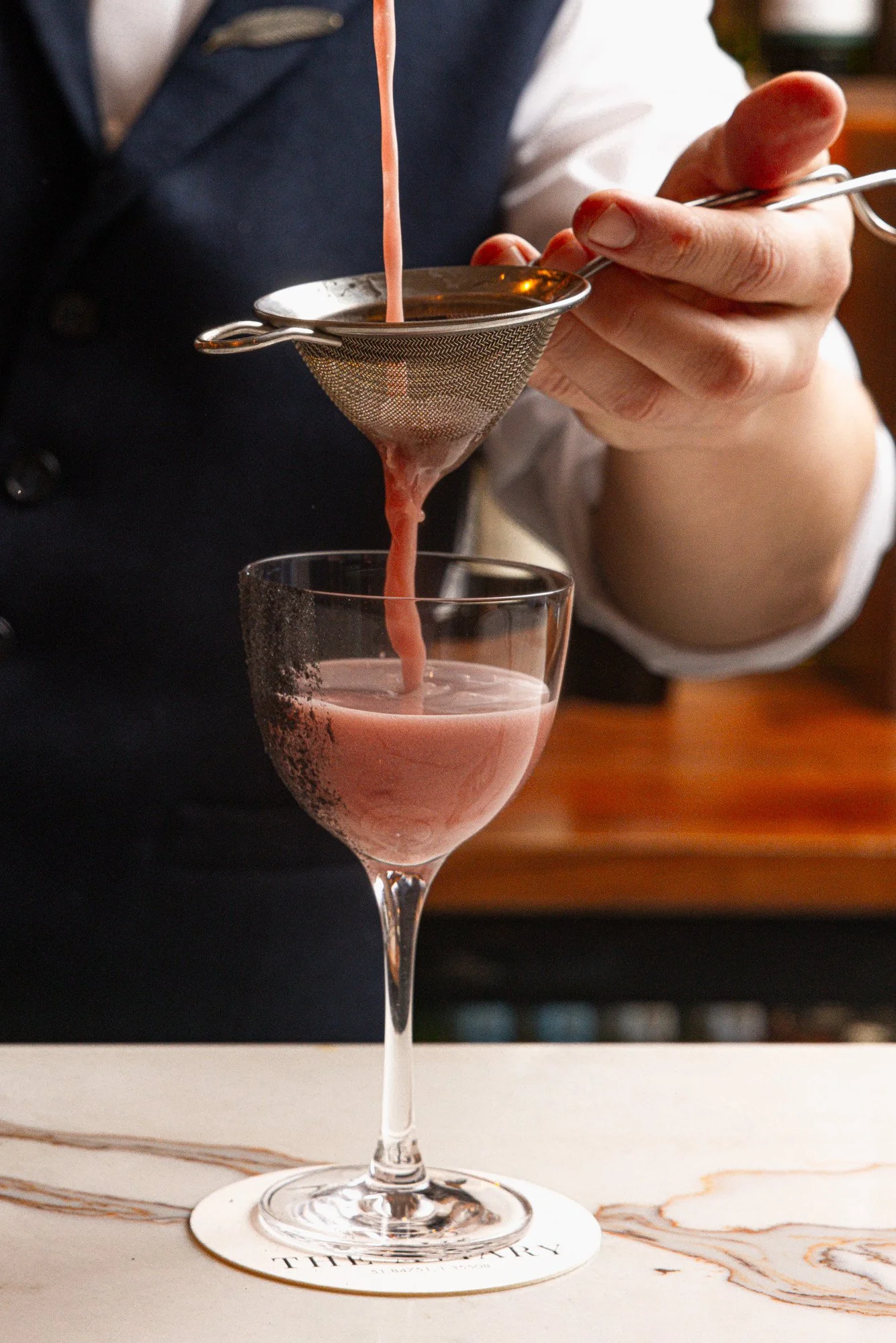 Hospitality photographer image, pink cocktail strained into a coupe for bar menus and social, shot in Milton Keynes, Buckinghamshire, venue marketing in St Ives, Cornwall, for use in London and Torquay, Devon.