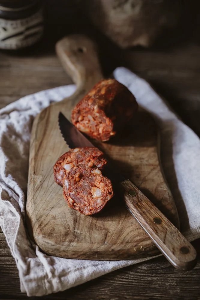 Commercial butchery photography, sliced chorizo on a wooden board with knife for website and social, shot in Oxford, Oxfordshire, independent butcher based in Exeter, Devon, for use in London and Cheltenham, Gloucestershire.