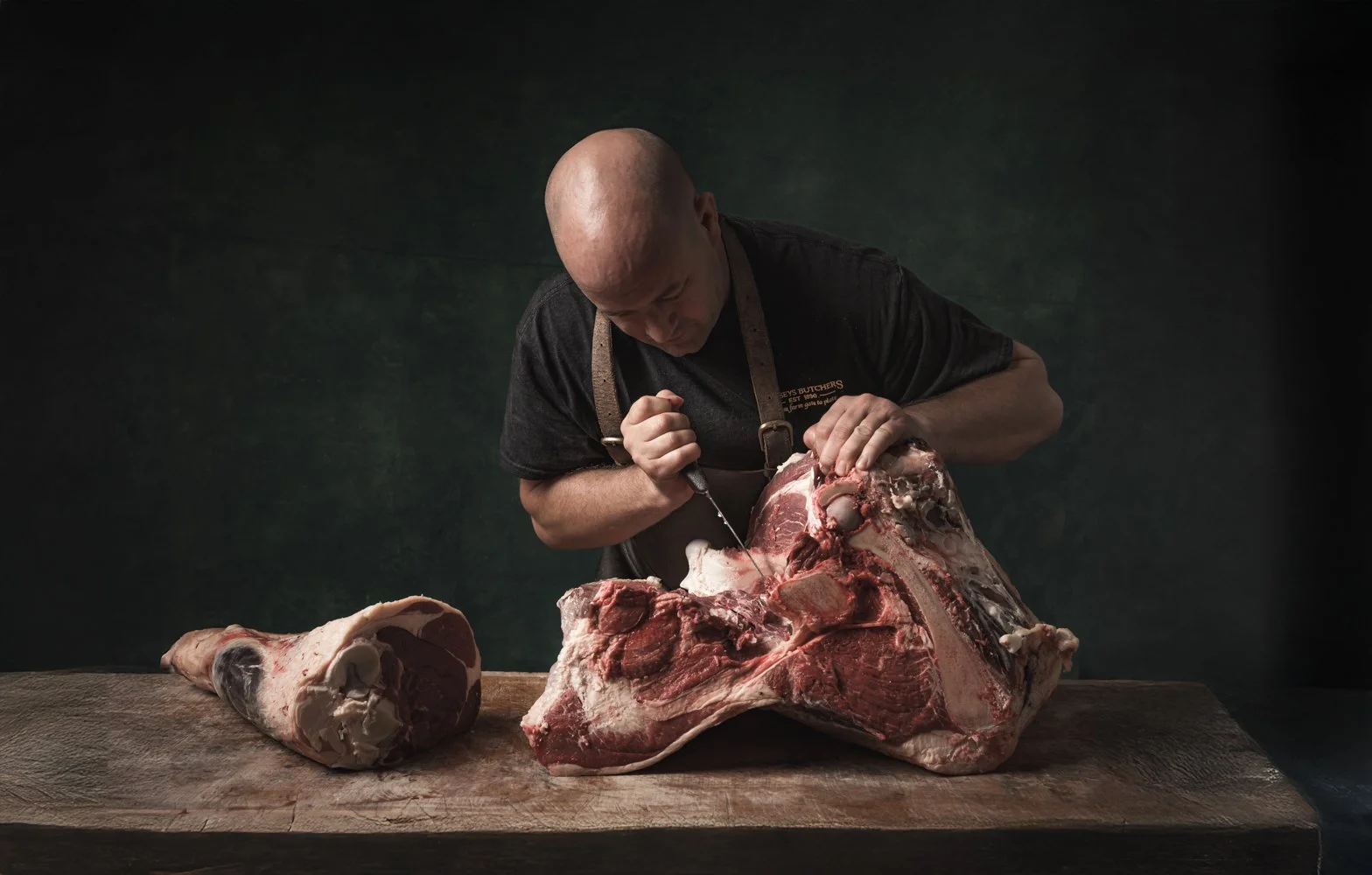 Commercial butchery photography, butcher breaking down a leg of beef on the block for website, menus and PR, shot in Cheltenham, Gloucestershire, butcher based in Exeter, Devon, for use in London and Oxford, Oxfordshire.