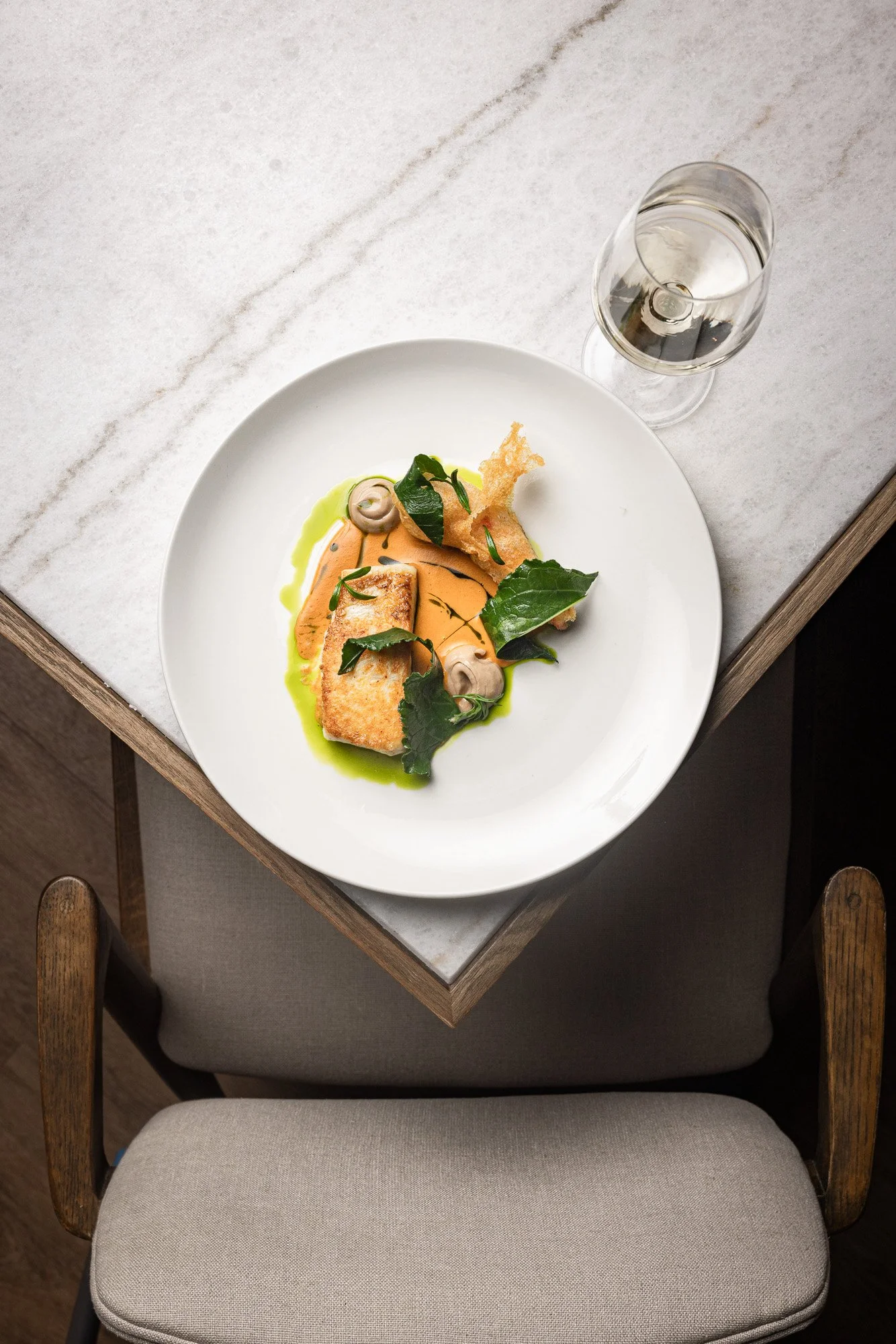Hospitality image, fish course with wine glass on marble for menus and web banners, shot in Plymouth, Devon, venue marketing in Cirencester, Gloucestershire, for use in London and Cardiff, Wales.