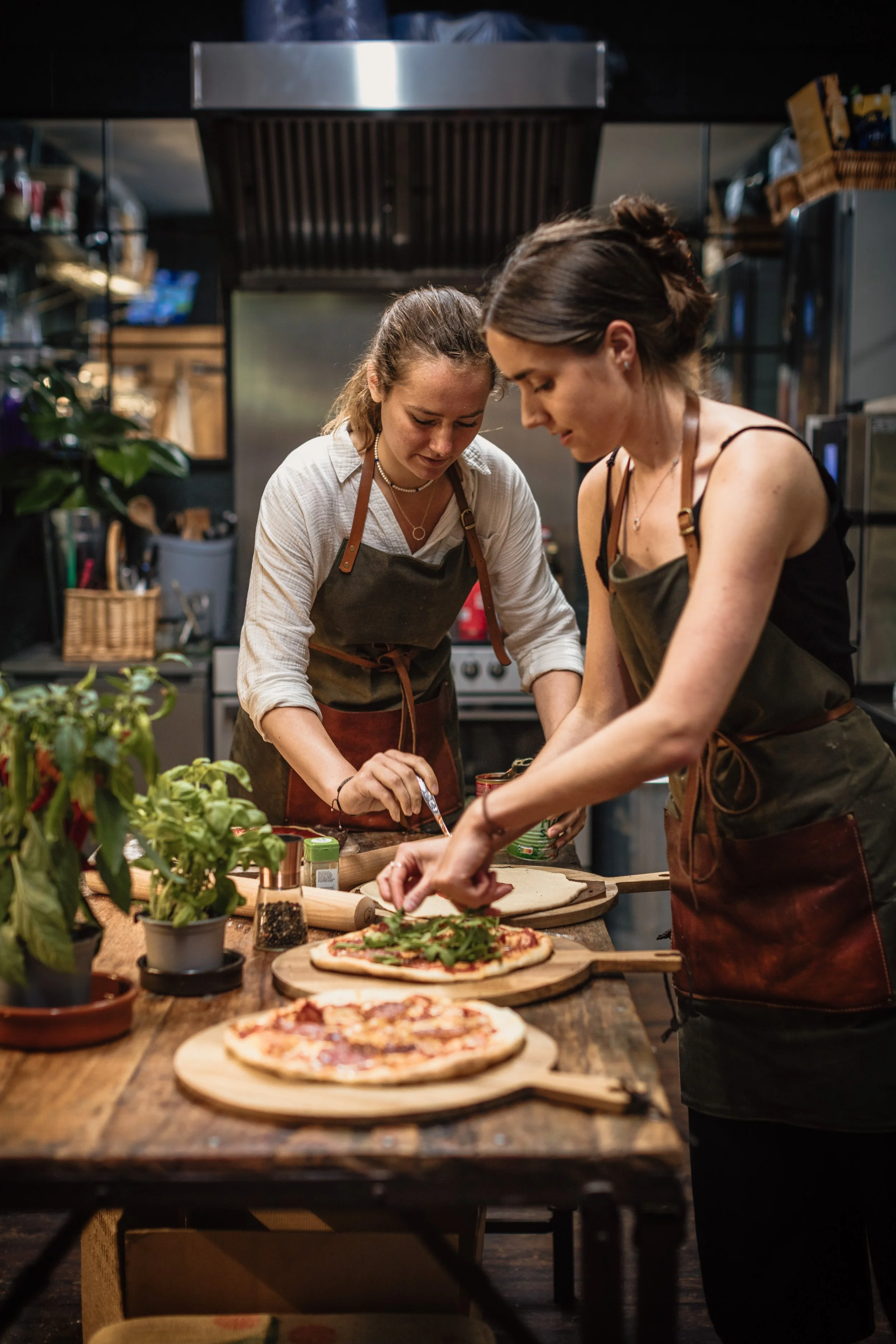 Two members of the Kenton Park Estate team preparing pizzas together at a kitchen worktable, photographed for menus, brochures and visitor-experience marketing.