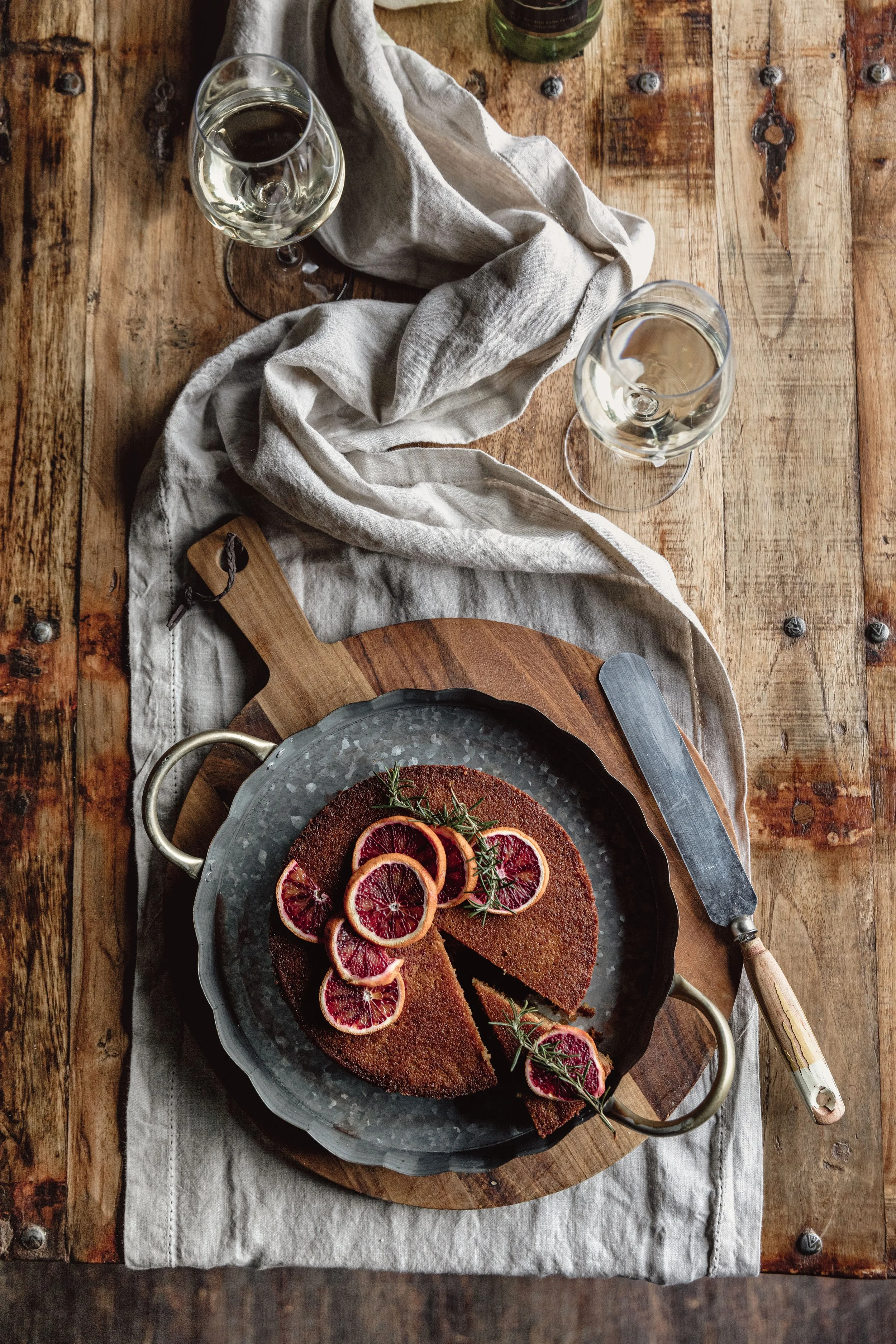 Blood orange cake decorated with thin rounds of blood orange, photographed overhead with rustic table styling for Kenton Park Estate’s menus and hospitality brochure