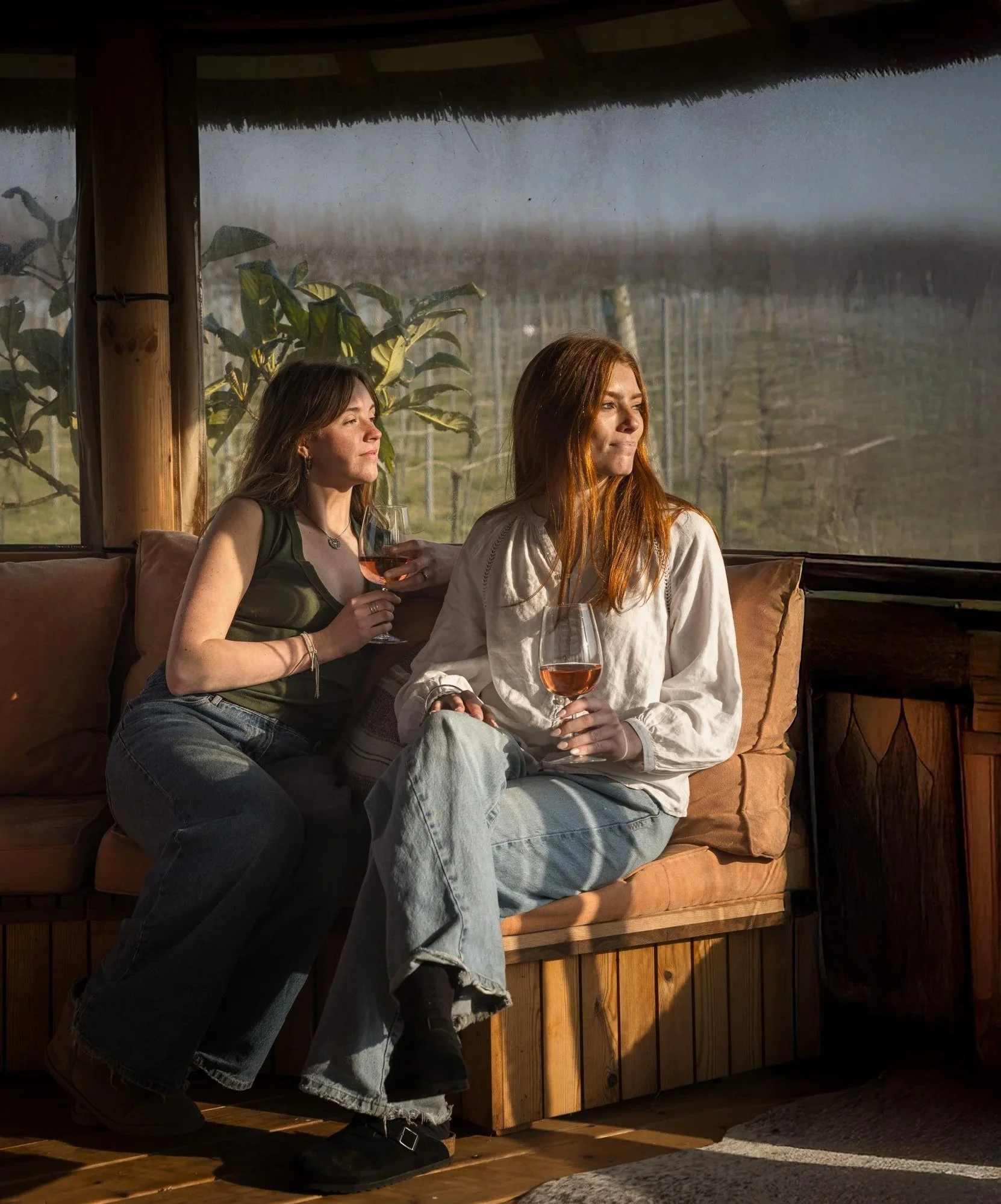 Two women sharing Kenton Park Estate wine inside a warm wooden vineyard shelter, photographed near Exeter to promote the estate’s relaxed visitor experience.