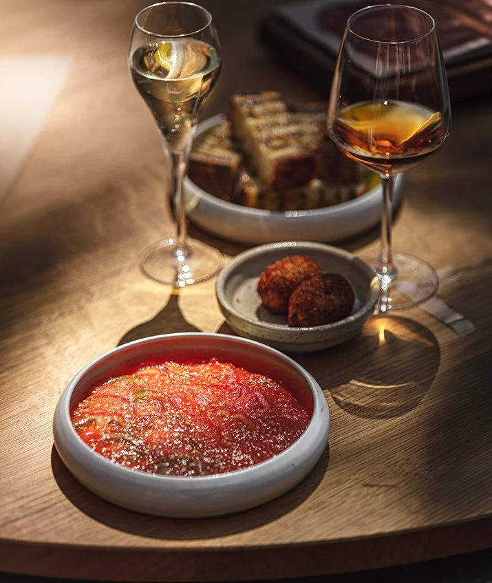 Commercial restaurant photograph of a Paco Tapas table with a vivid red plated dish, croquettes and wine, created in Bristol for hospitality websites, editorial and social media content.