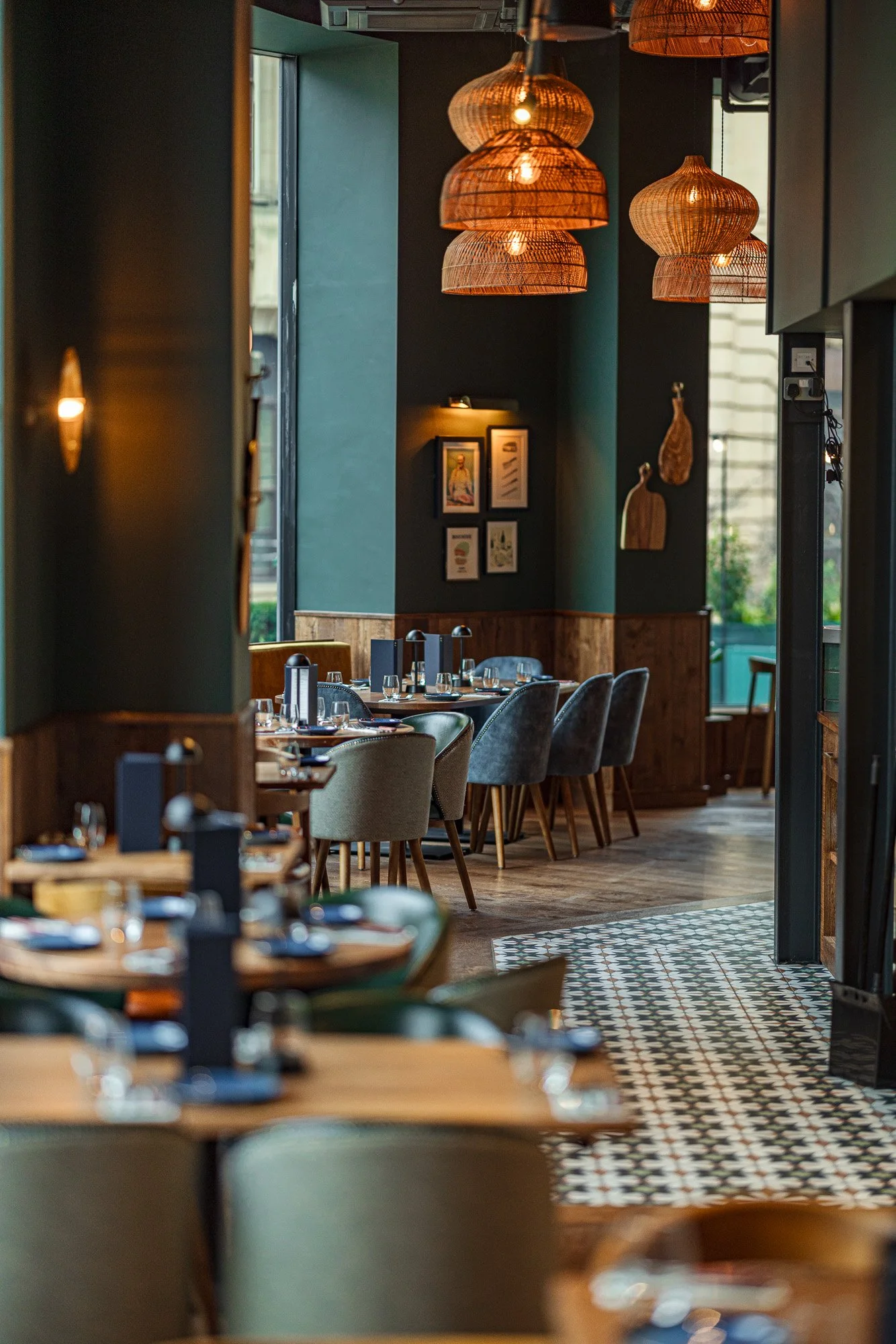 Commercial restaurant interior at The Cow & Sow in Birmingham, showing deep teal walls, woven pendant lights, patterned flooring and dining tables extending through the room.