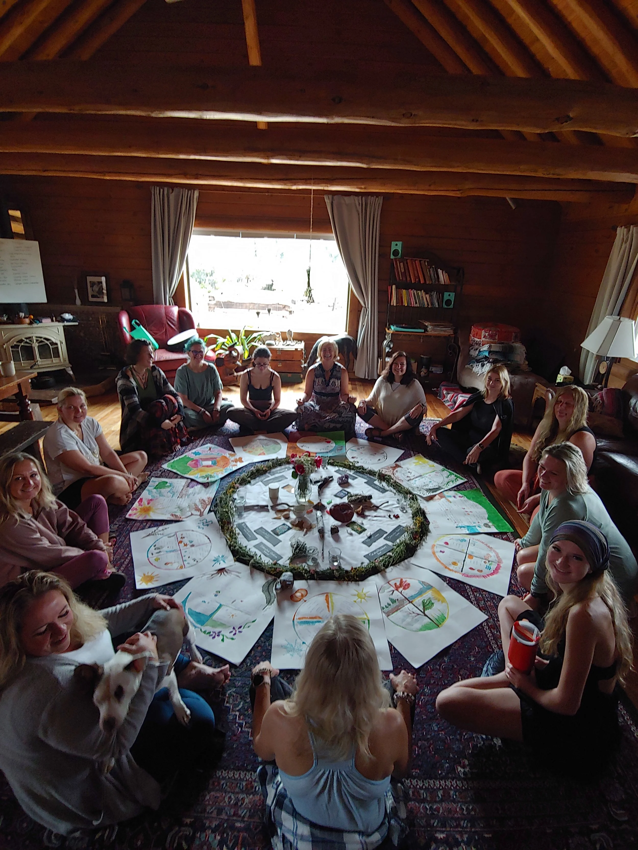 Slavic Sisters sitting in a circle with artwork, sitting in a cozy wooden room with a large window and curtains.