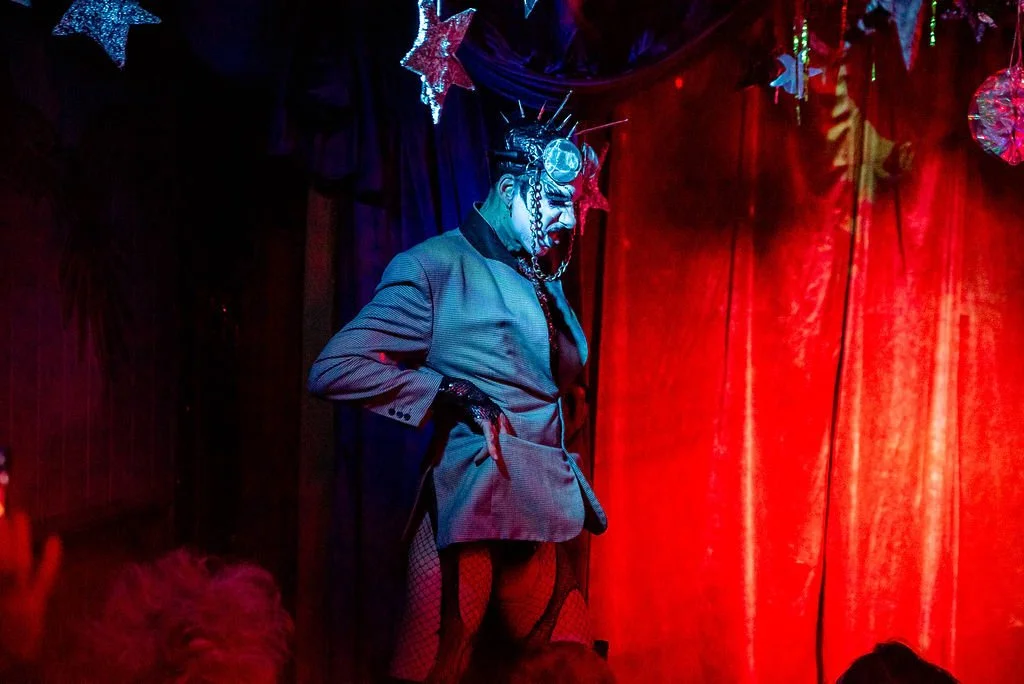 Performer in costume on stage with red lighting and star decorations