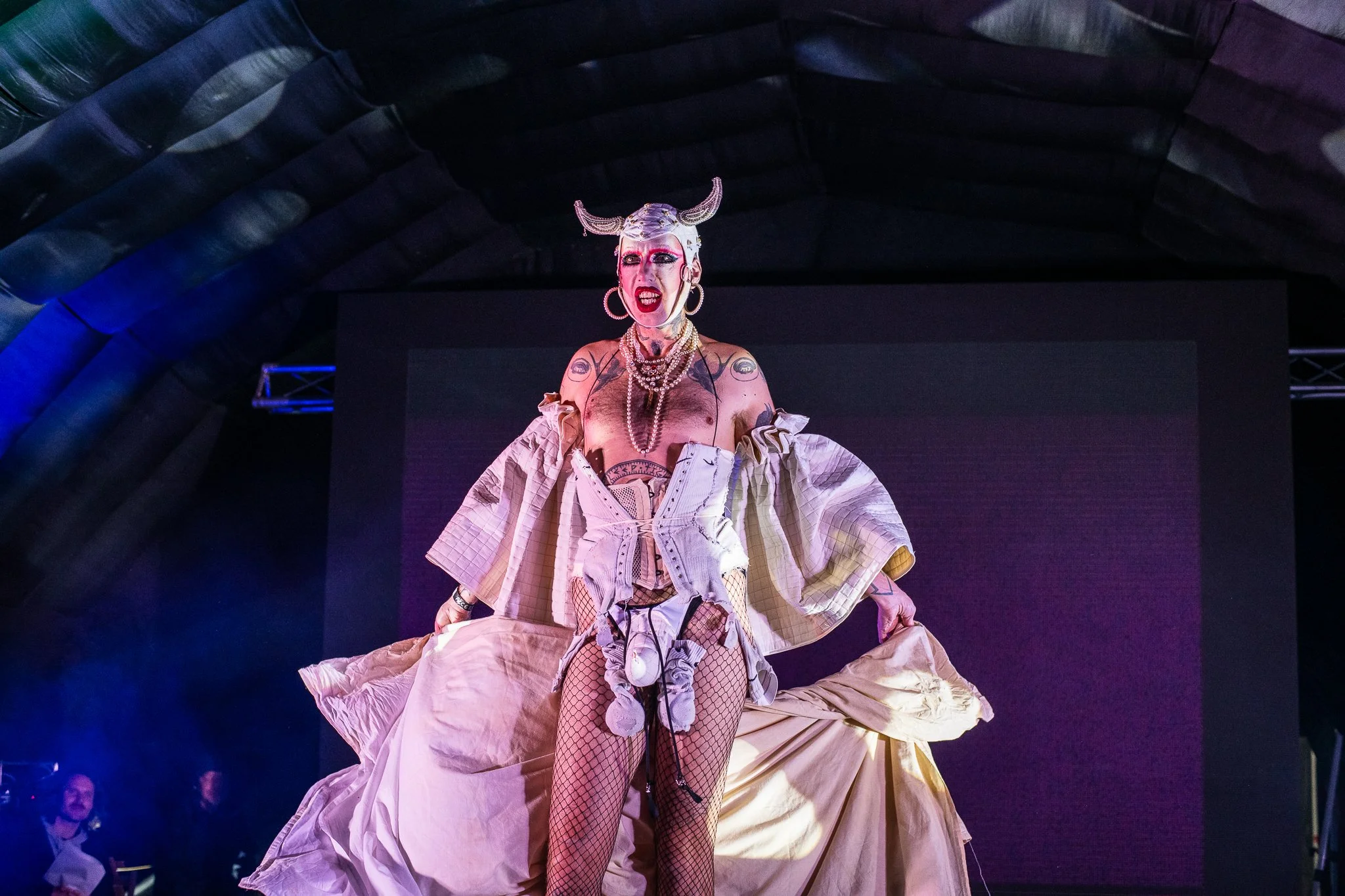 A performer on stage wearing a dramatic white costume with a horned headpiece