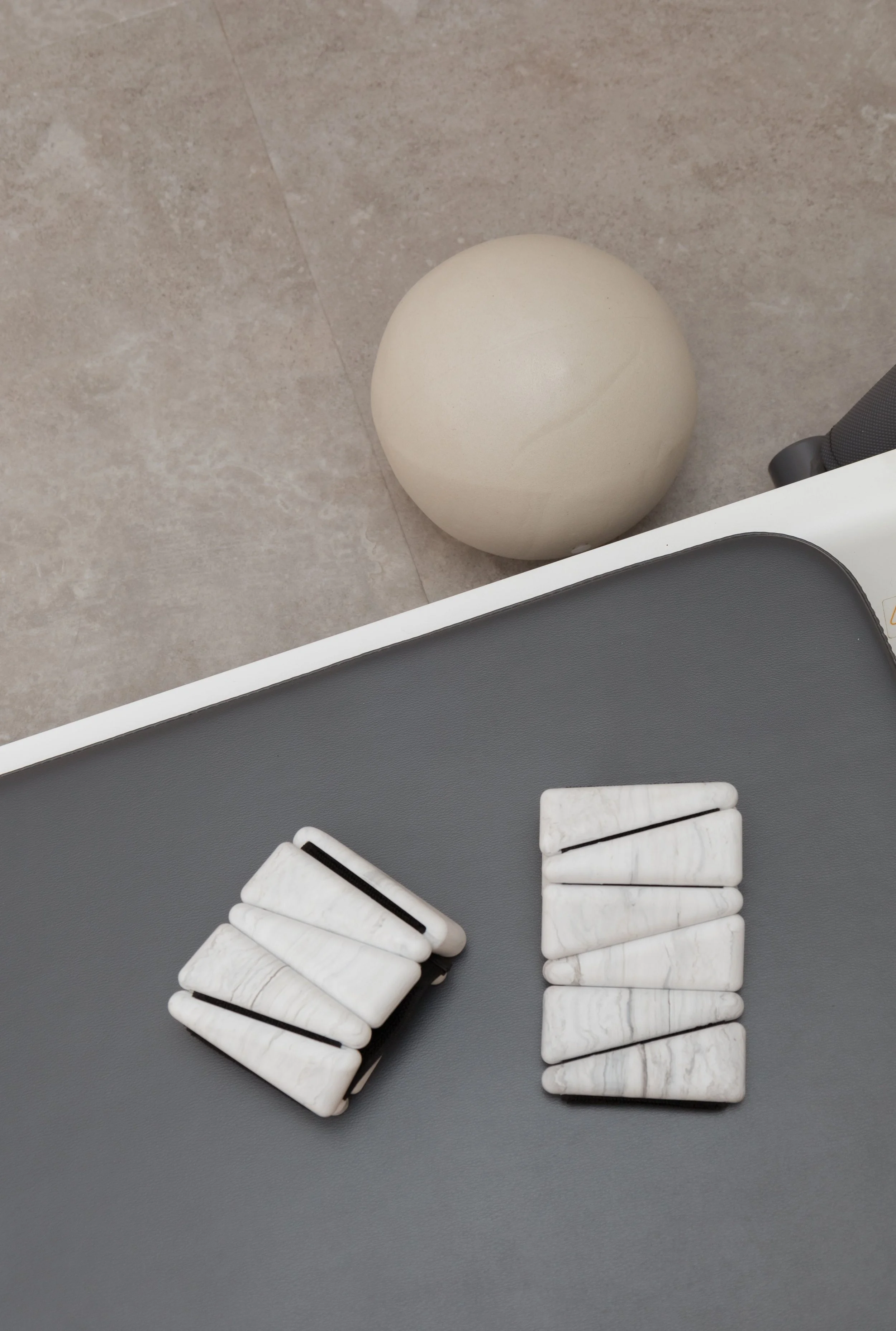 A set of marble-patterned dominoes on a gray surface, with a round beige object and a piece of black and white furniture nearby.