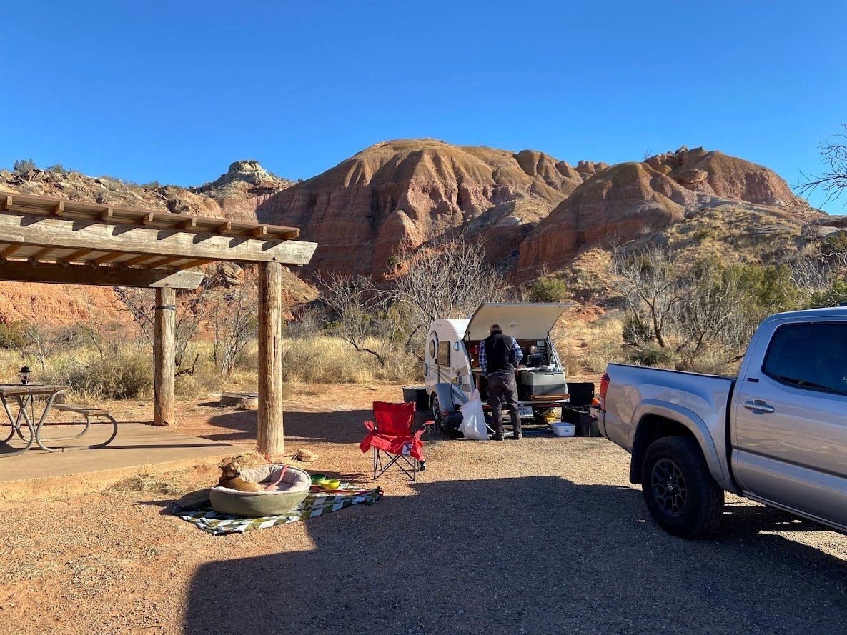 RV campsite with man leaning over trialer.