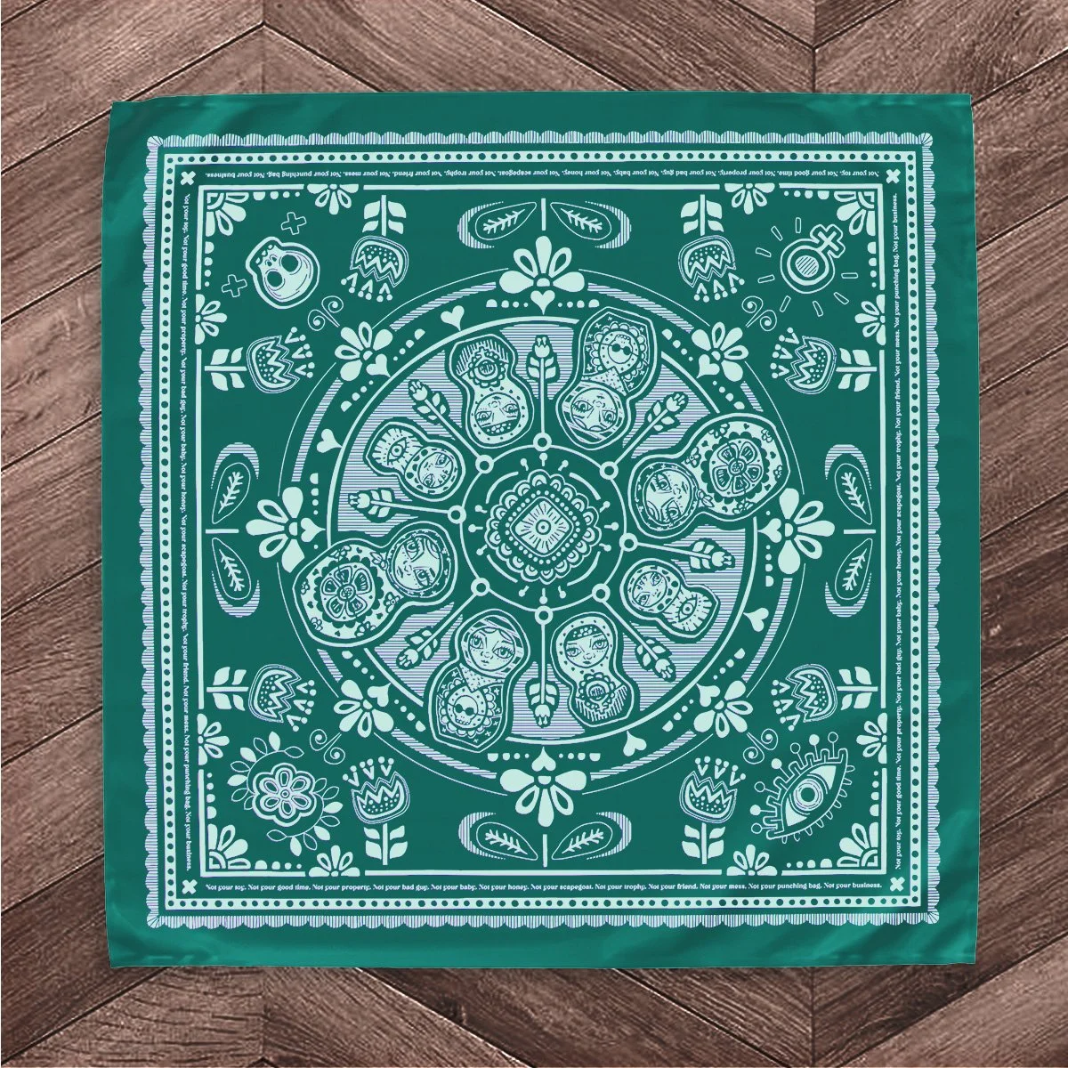 Sugar Camp Matryoshka nesting doll cotton feminist bandana in turqouise, featuring nesting doll matryoshka motif flat on a wooden floor.