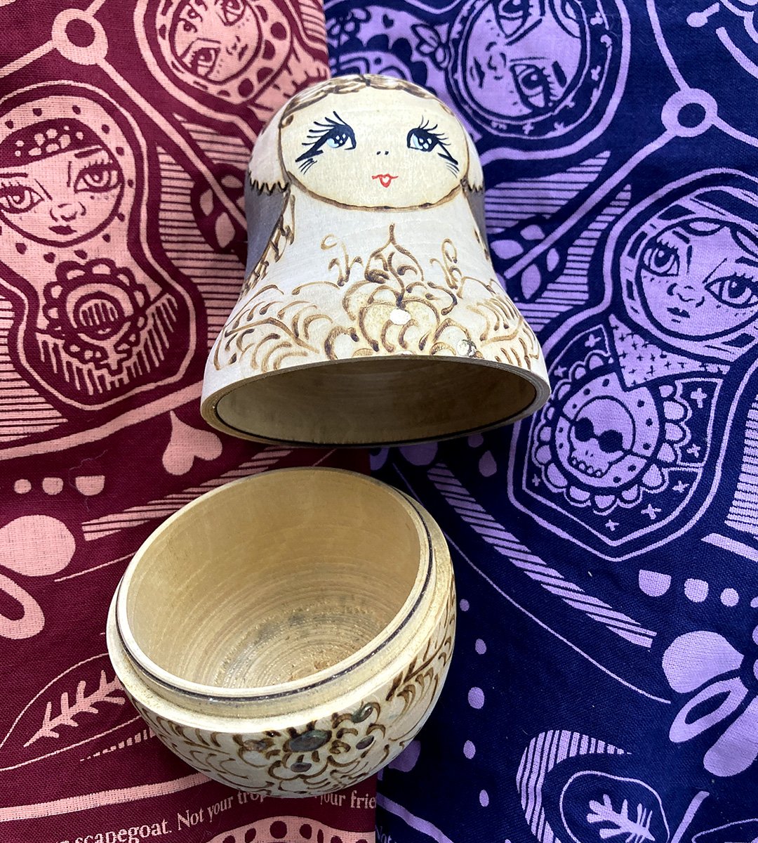 vintage wooden nesting doll sits atop two sugar camp matryoshka bandanas.