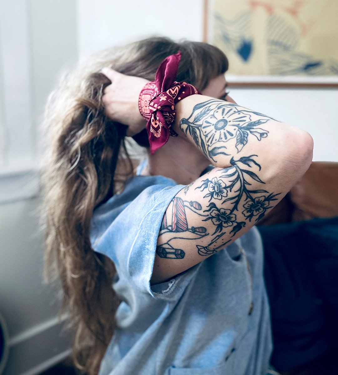 young blond woman tossles sugar camp feminist cotton bandana into top lose ponytail updo.