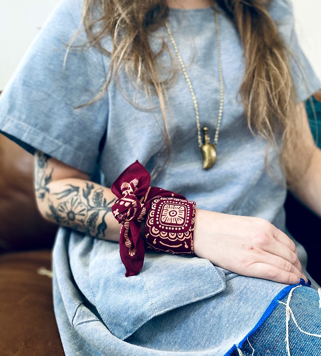 blond woman wears sugar. camp cotton bandana tied around wrist, like a bracelet band.