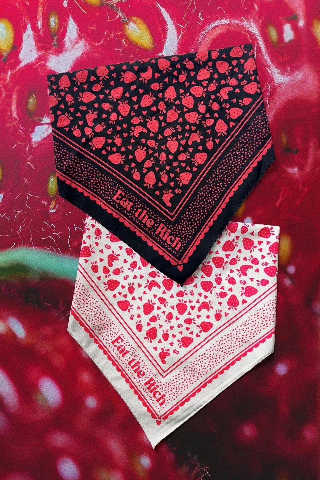 Black and cream “Eat the Rich” bandanas with red fruit-and-symbol print displayed over macro strawberry texture