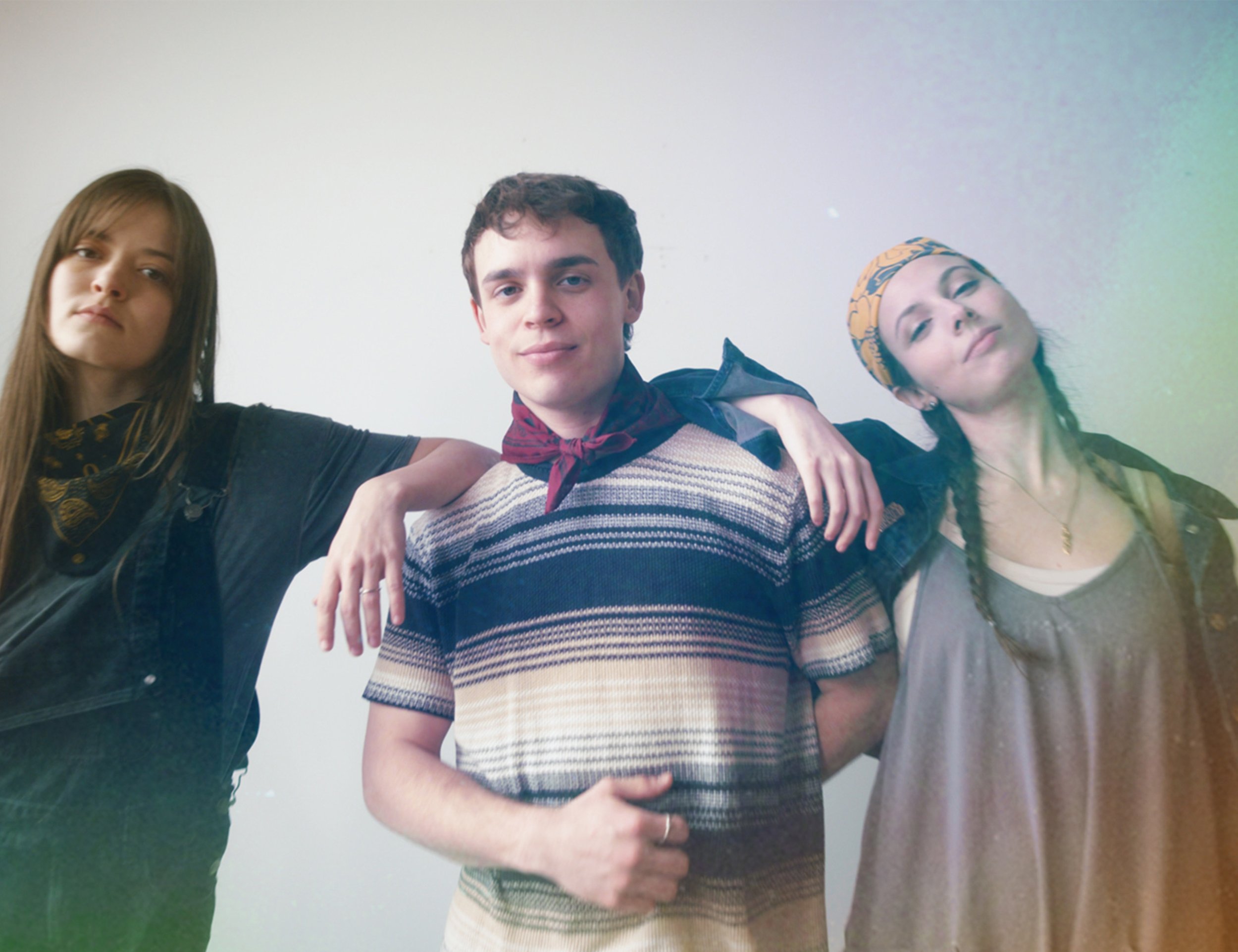 Three diverse young adults wearing bold statement bandanas in different styles — around the neck and as head wraps — showcasing inclusive, gender-neutral, activist-inspired fashion.