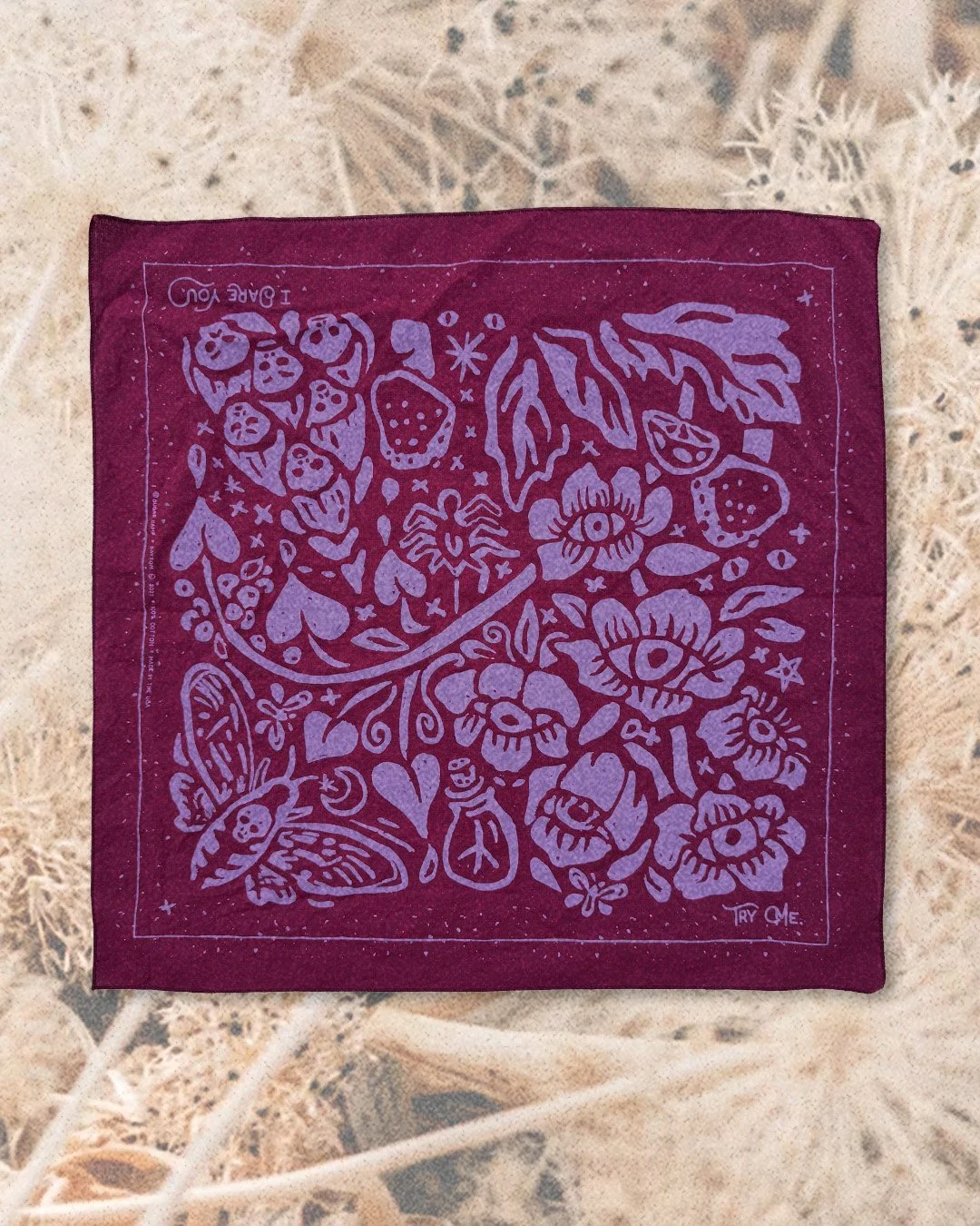 Poisoner’s Garden bandana in poison berry pink, laid flat on bed of dandelion fluff heads.