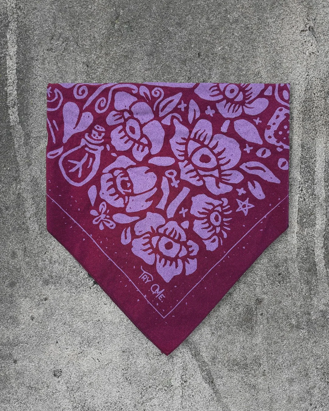 Poisoner’s Garden bandana by Sugar Camp in poison berry pink, folded into a triangle on concrete background.