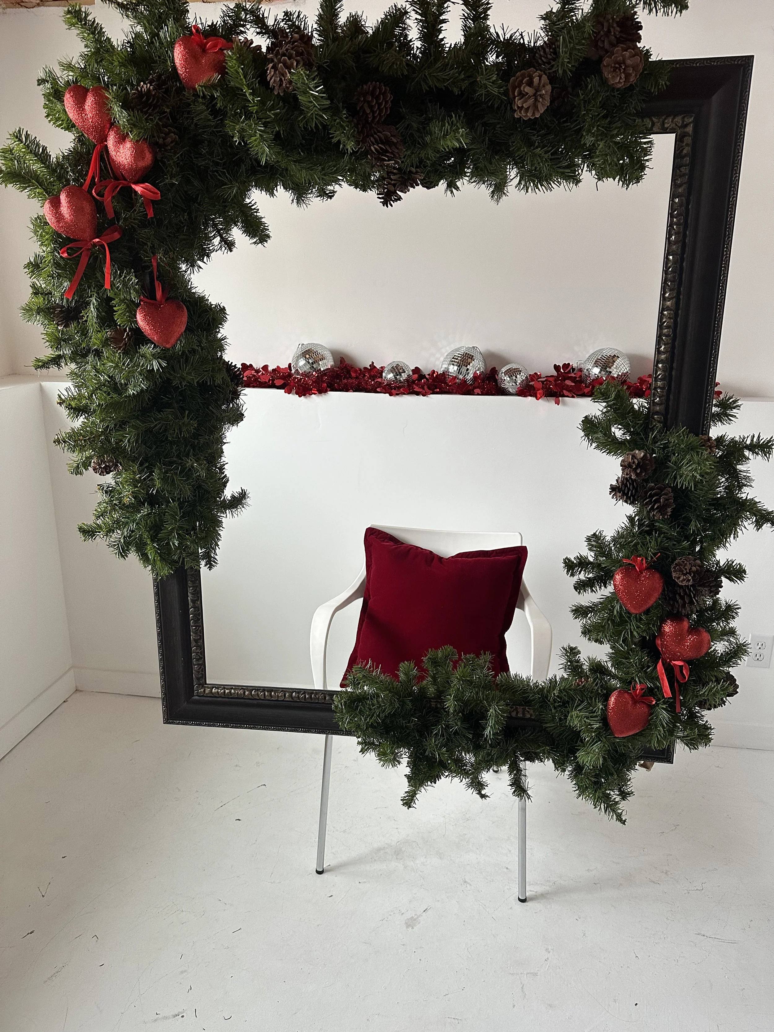 Romantic couples photography in an Edmonton photo studio with Valentine’s garland, soft red tones, and a cozy, intimate backdrop.